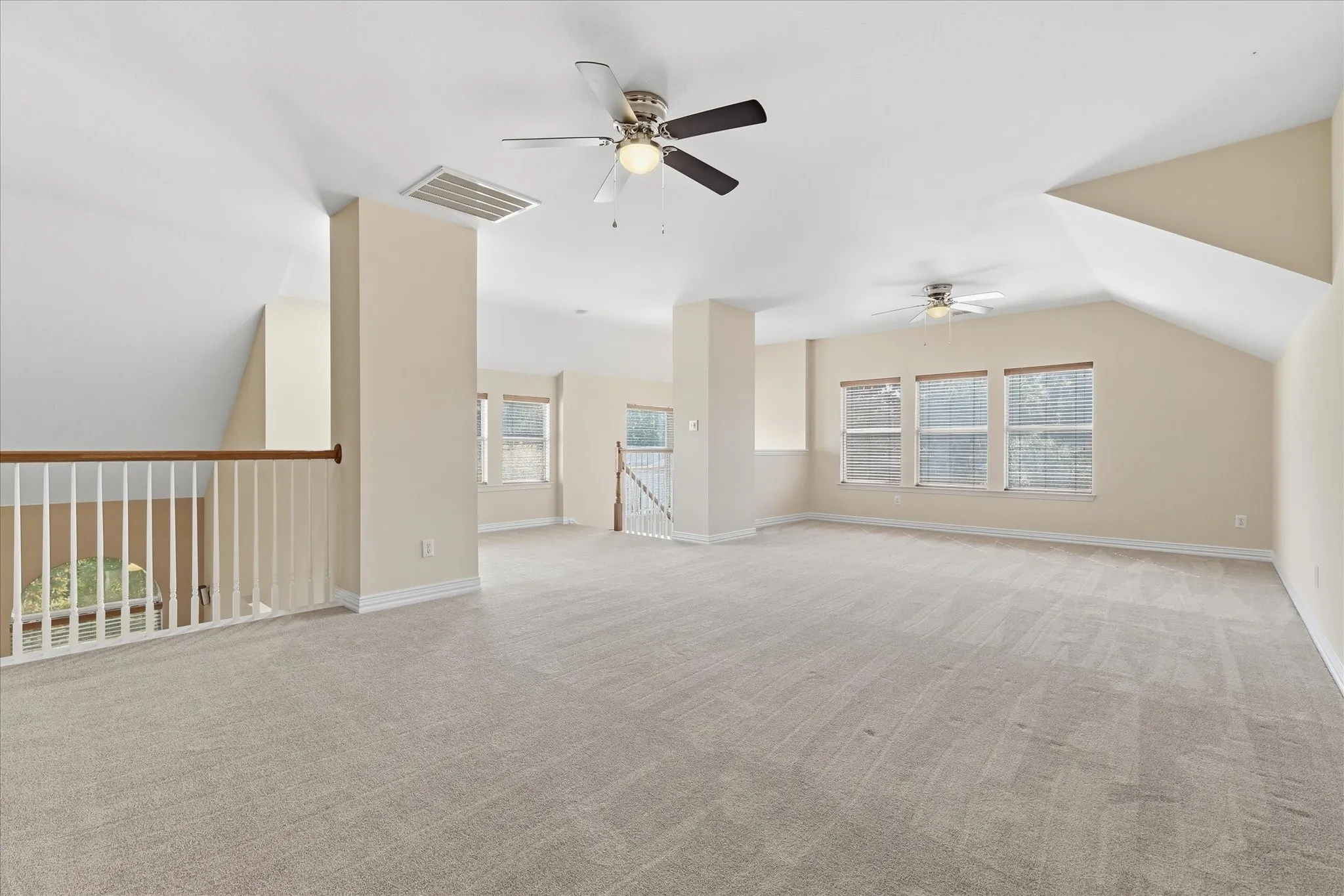 Open-concept Game room featuring neutral-toned walls, light grey carpeting, and a ceiling fan with integrated lighting. Also featuring an overlook open to the living room.