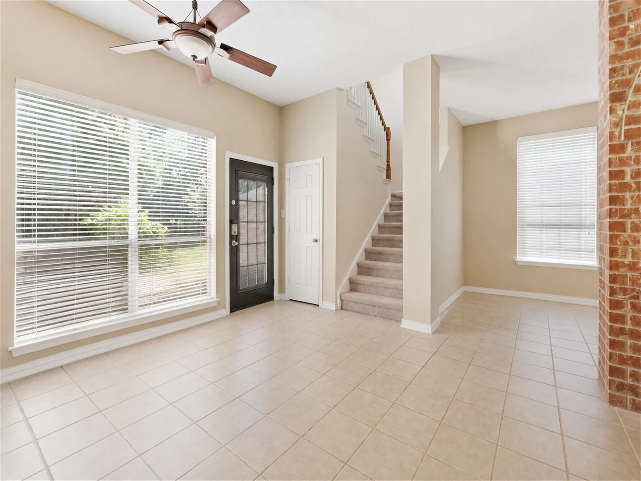 Neutral-toned walls complement the light-colored tile flooring. Large window and Ceiling Fan.