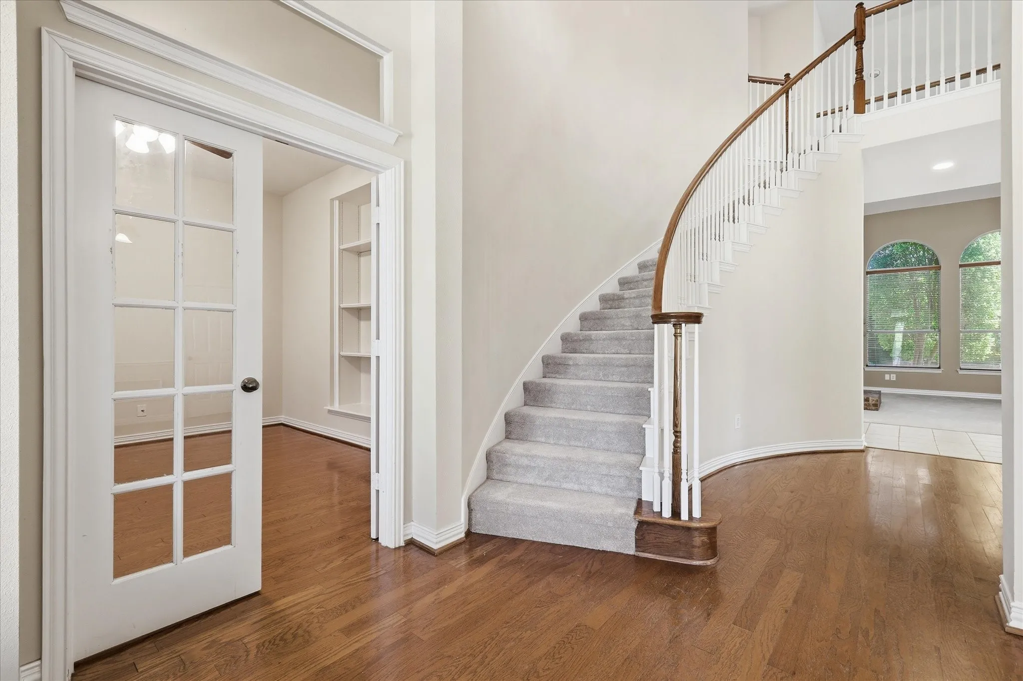 Entry foyer featuring a curved staircase with carpet and wood-finish handrail, wood-finish flooring, and a French door