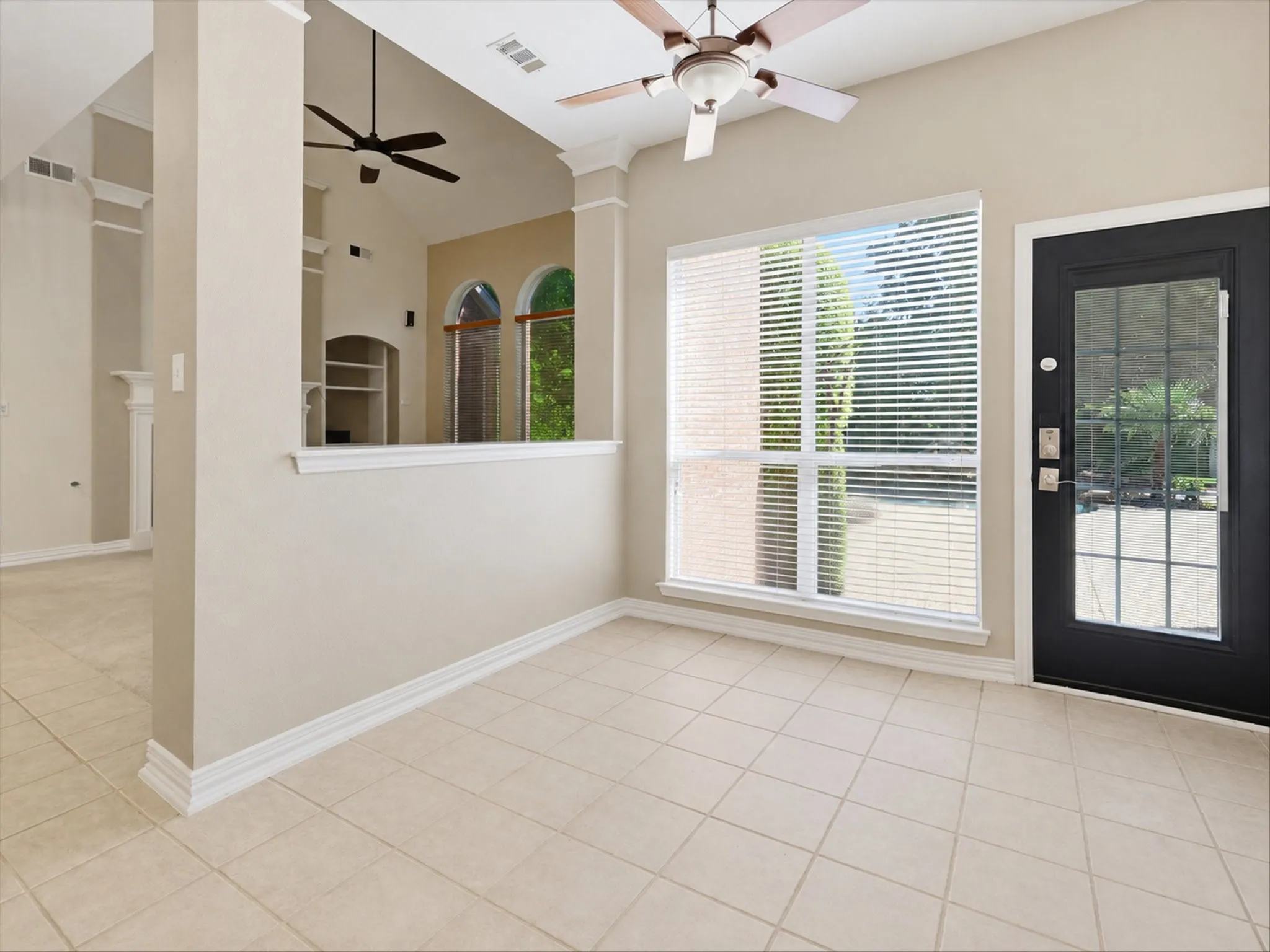 Neutral-toned walls complement the light-colored tile flooring. Large window and half wall.