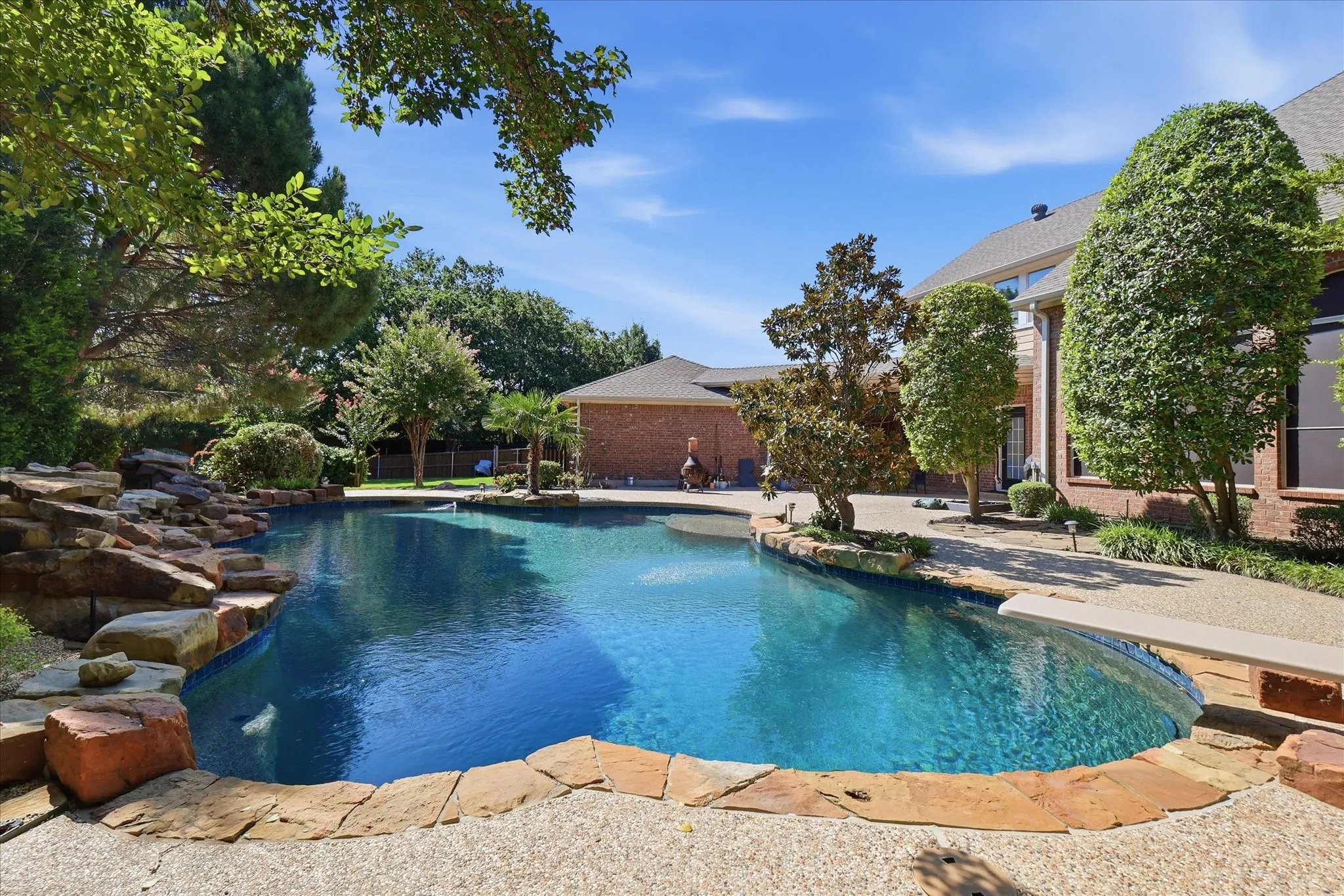 Expansive backyard featuring a custom-shaped swimming pool with stone coping and a diving board