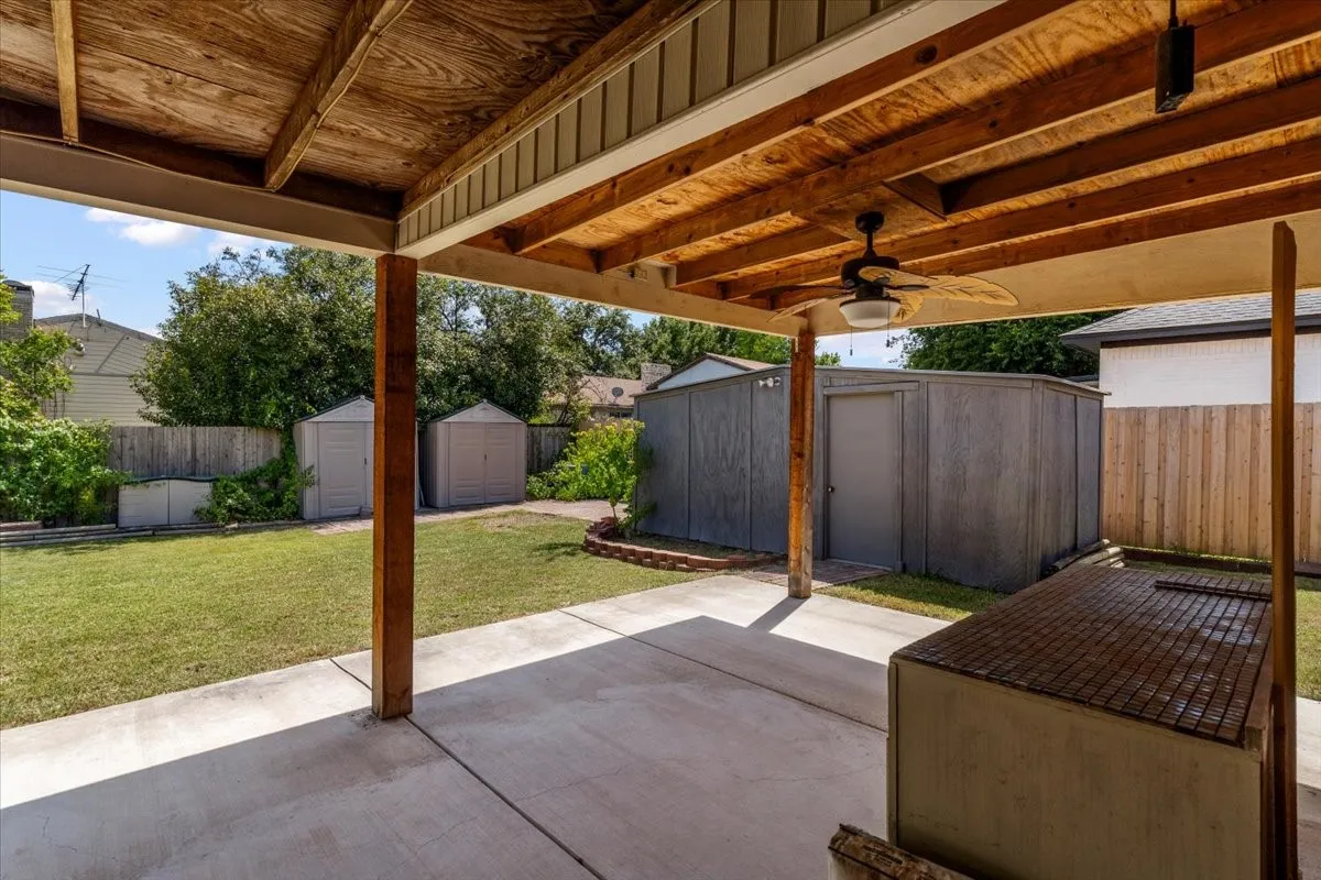 Covered patio featuring a ceiling fan, concrete flooring, and exposed wood beams
