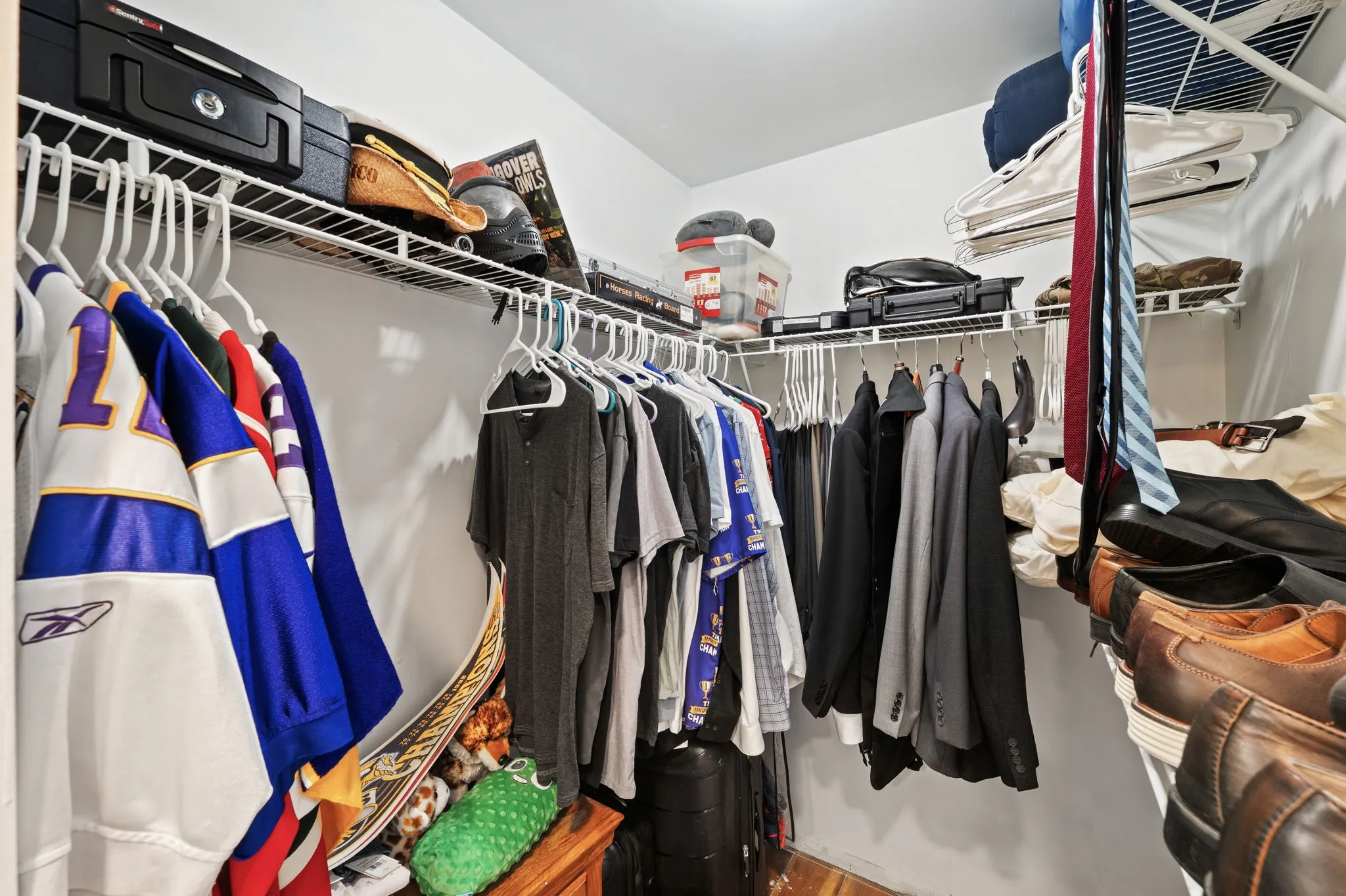 Walk-in closet with white walls, multiple hanging rods, and wire shelving