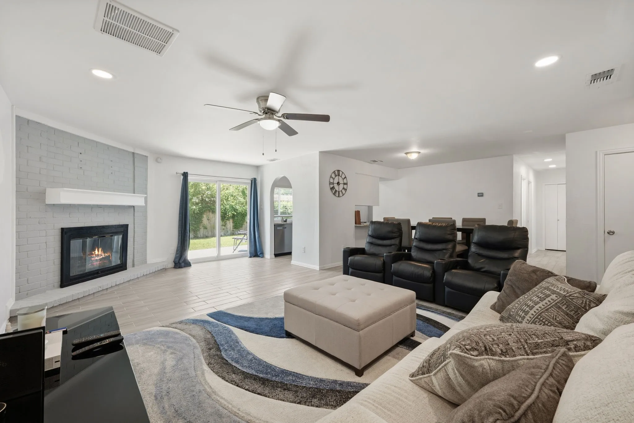 Spacious living area featuring a corner fireplace with a white brick surround, recessed lighting, and wood-finish flooring