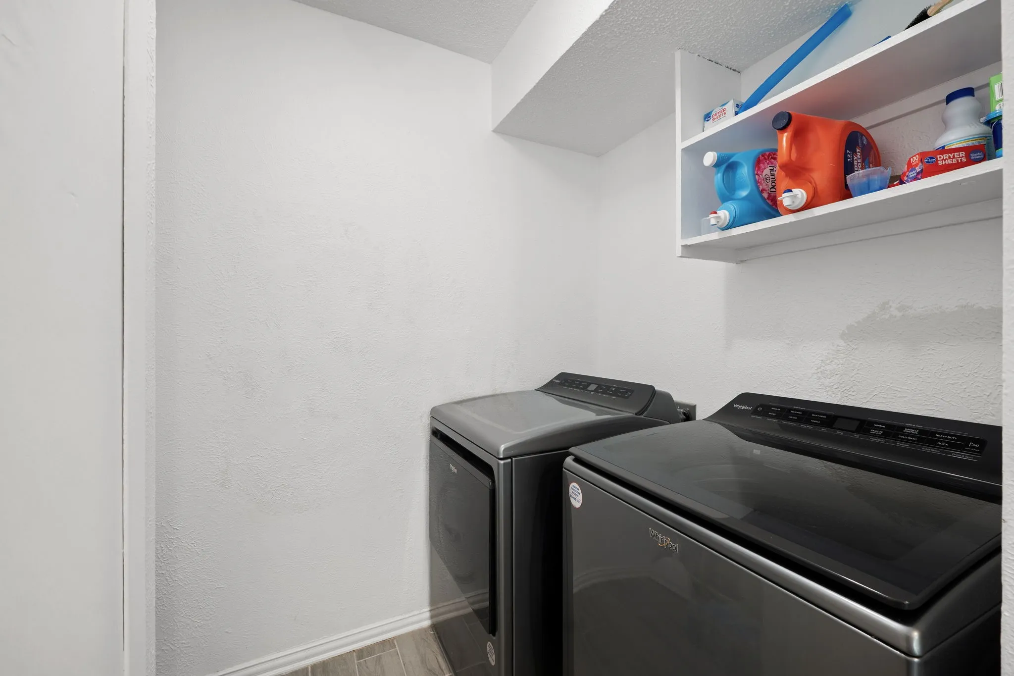 Dedicated laundry area featuring wood-finish flooring and an upper storage shelf