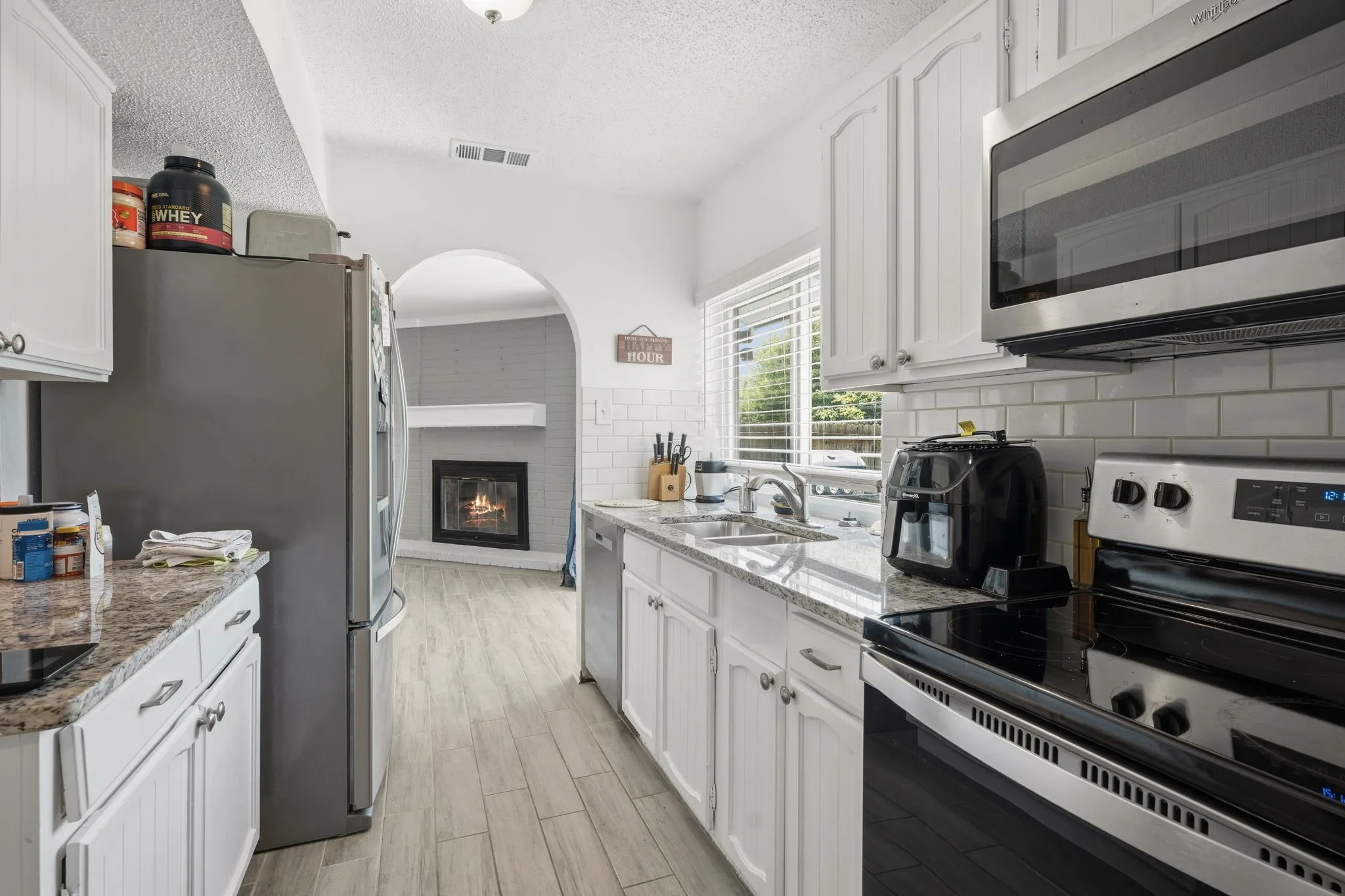 Kitchen featuring white cabinetry, granite countertops, tile flooring, and stainless steel appliances