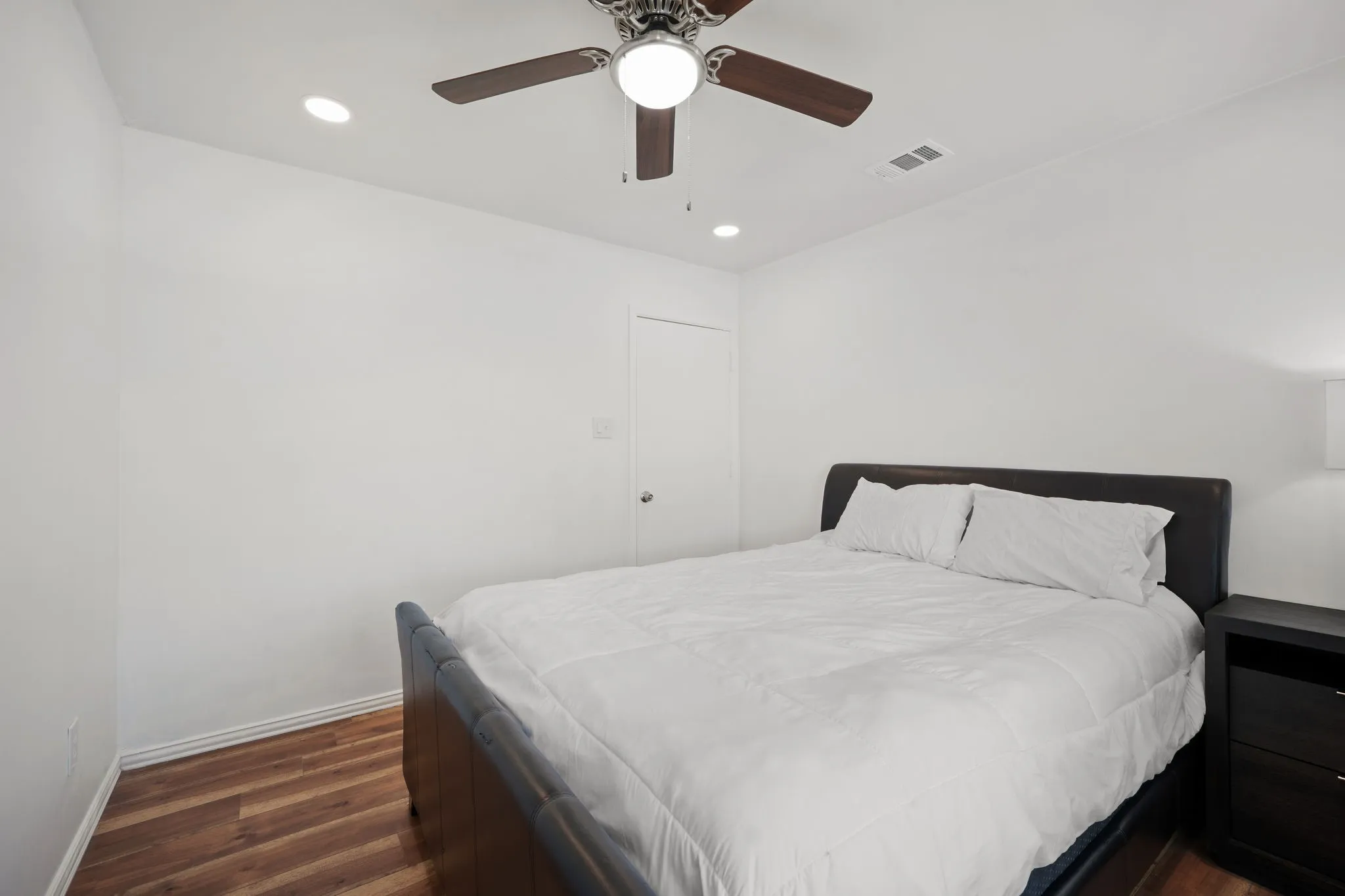 Bedroom featuring wood-finish flooring, white baseboards, a white door, recessed lighting, and a ceiling fan with integrated lighting
