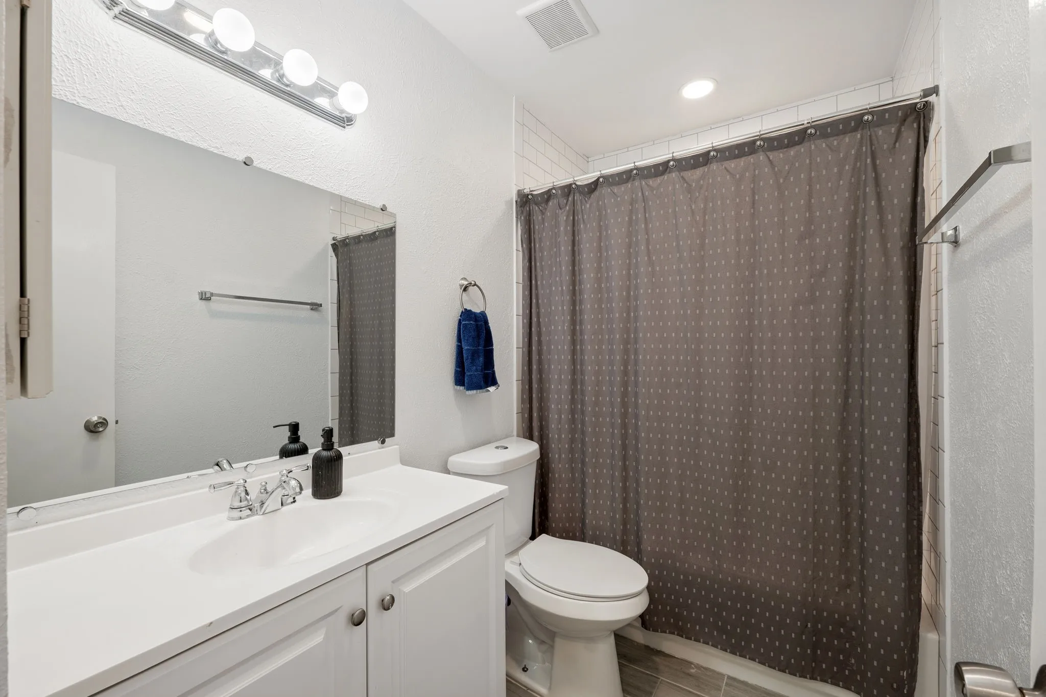 Bathroom featuring a white vanity with integrated sink, chrome faucet, and a large wall-mounted mirror