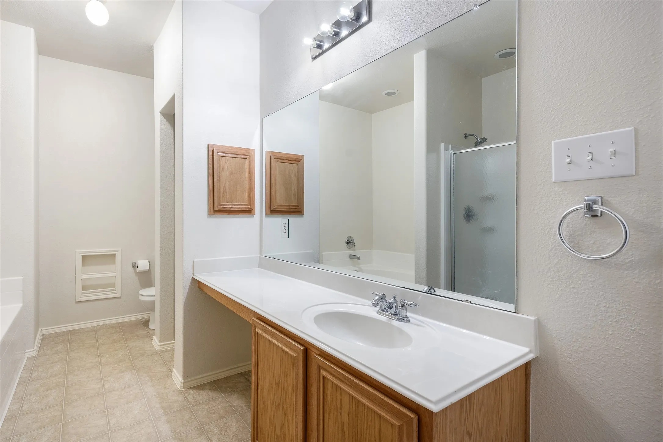 Bathroom vanity featuring a single basin, laminate countertop, and wood-finish cabinetry