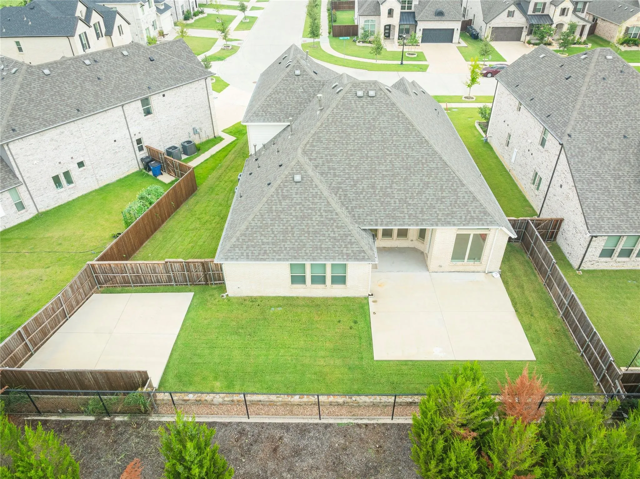 Expansive backyard featuring a manicured lawn, two concrete patios, and full fencing