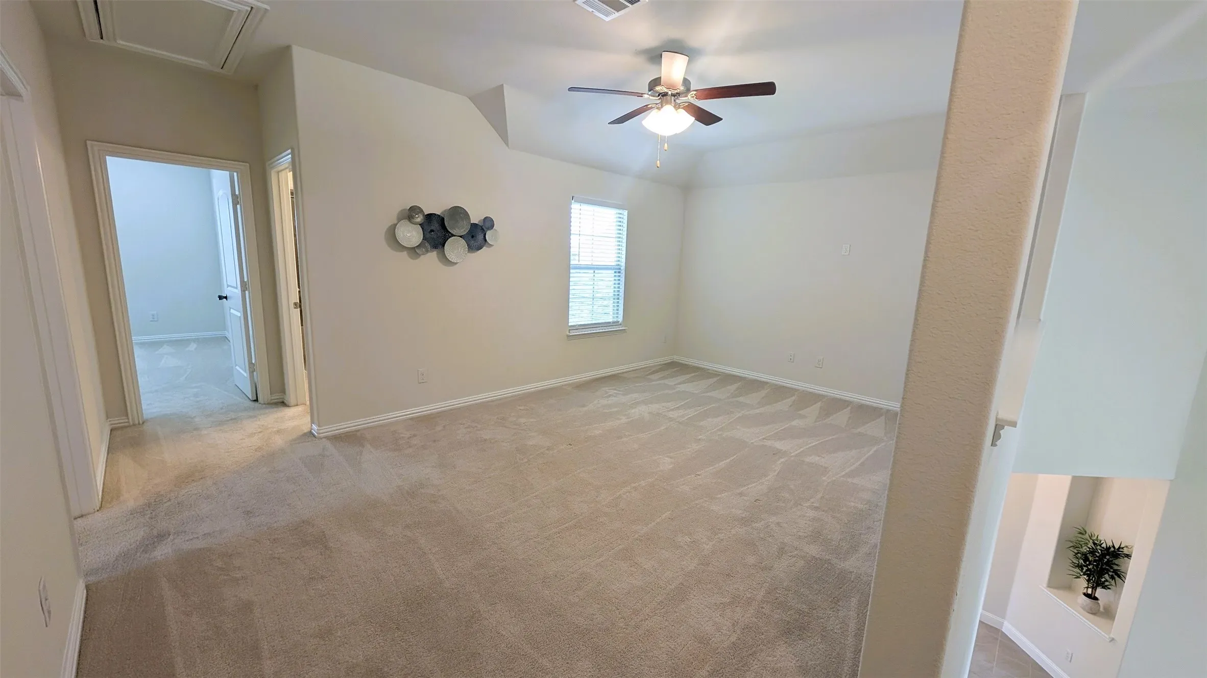 Carpeted room featuring a ceiling fan, a window with natural light, and two interior doors