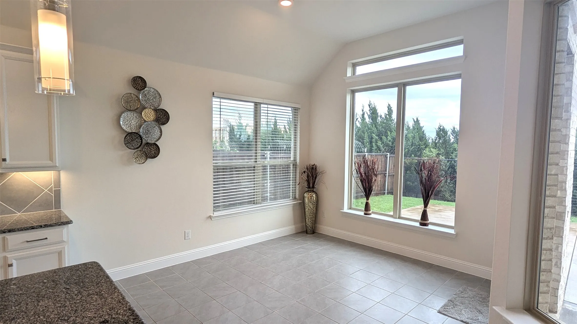 Vaulted ceiling room featuring large windows, a transom window, and tile flooring