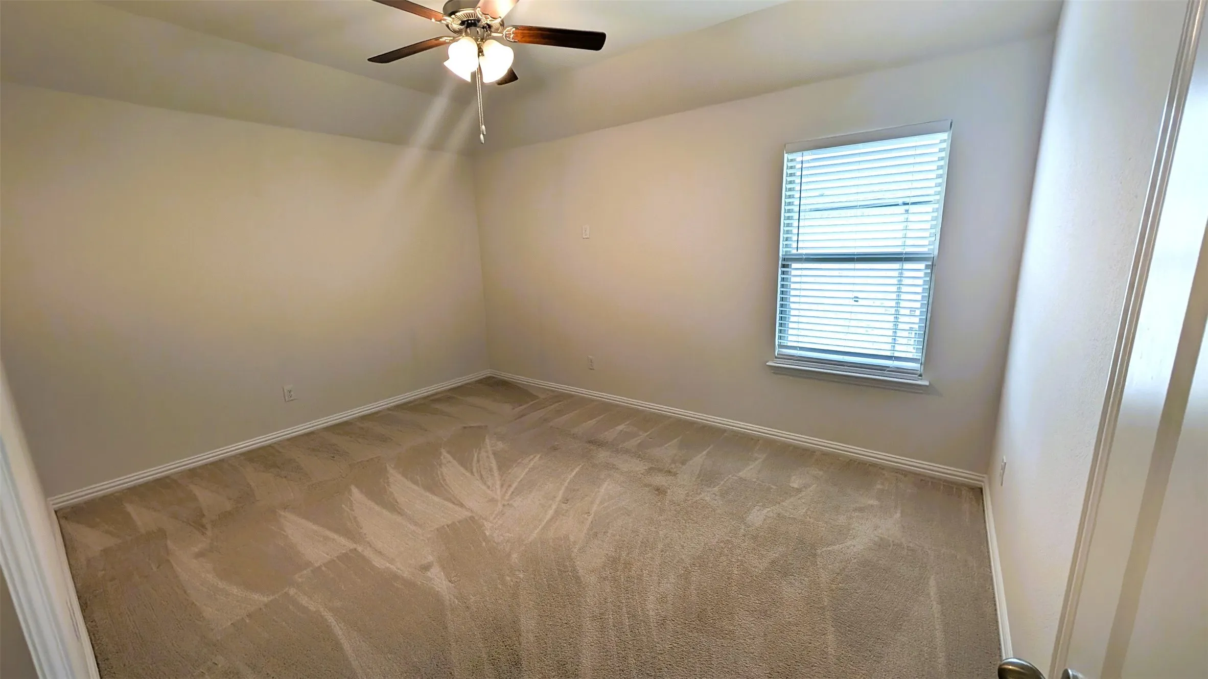 Carpeted room featuring a ceiling fan with light fixture, window with blinds, and neutral wall tones