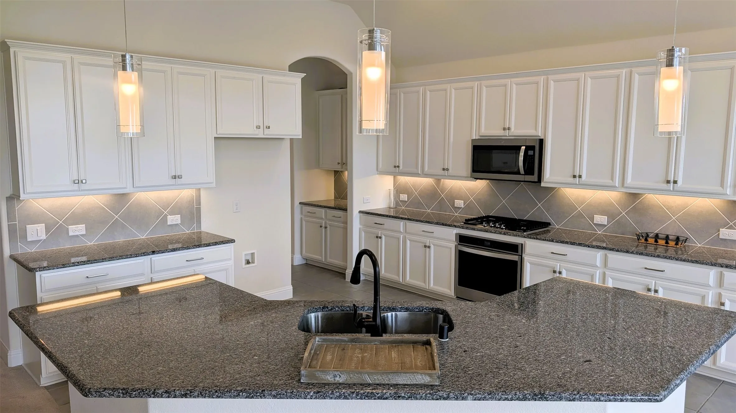Kitchen featuring a large island with an undermount sink, granite countertops, and white shaker-style cabinetry