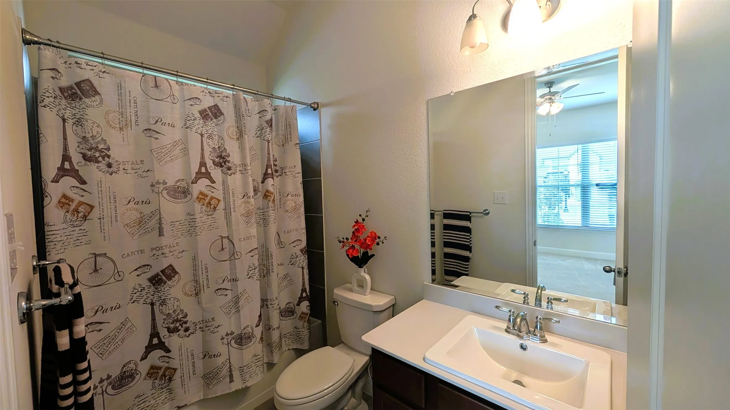 Full bathroom featuring a single vanity with an integrated sink, brushed nickel faucet, wall-mounted mirror, and overhead vanity lighting