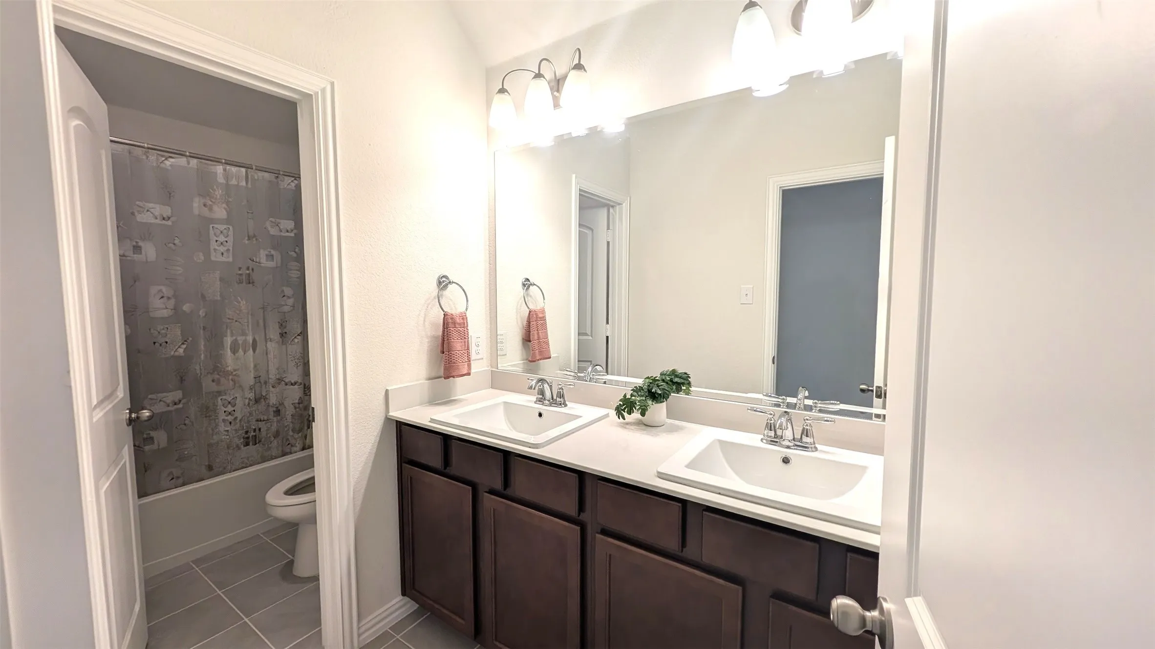 Double vanity with integrated sinks, light-toned countertop, and dark wood-finish cabinetry