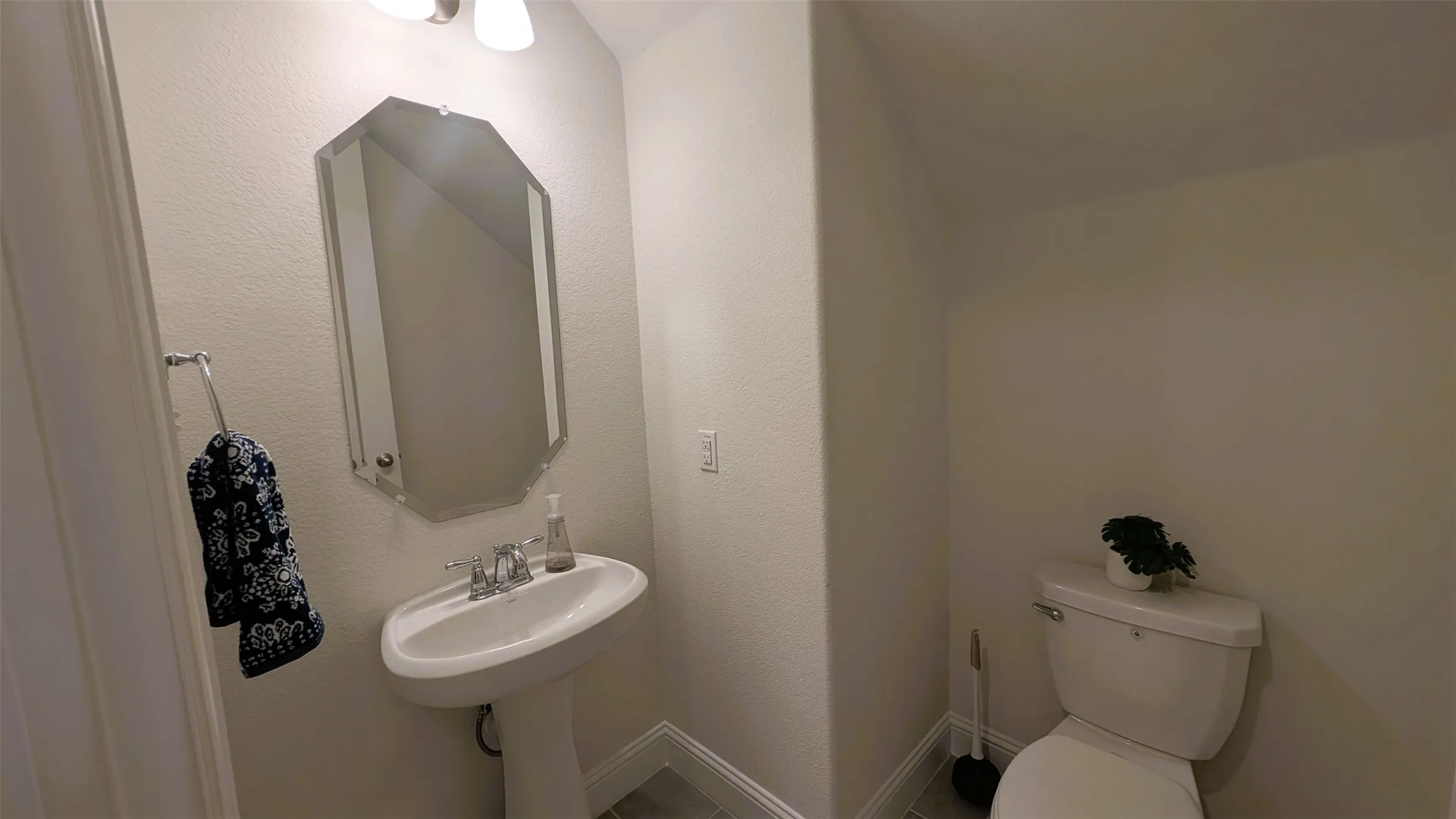 Pedestal sink with chrome-finish faucet and octagonal mirror