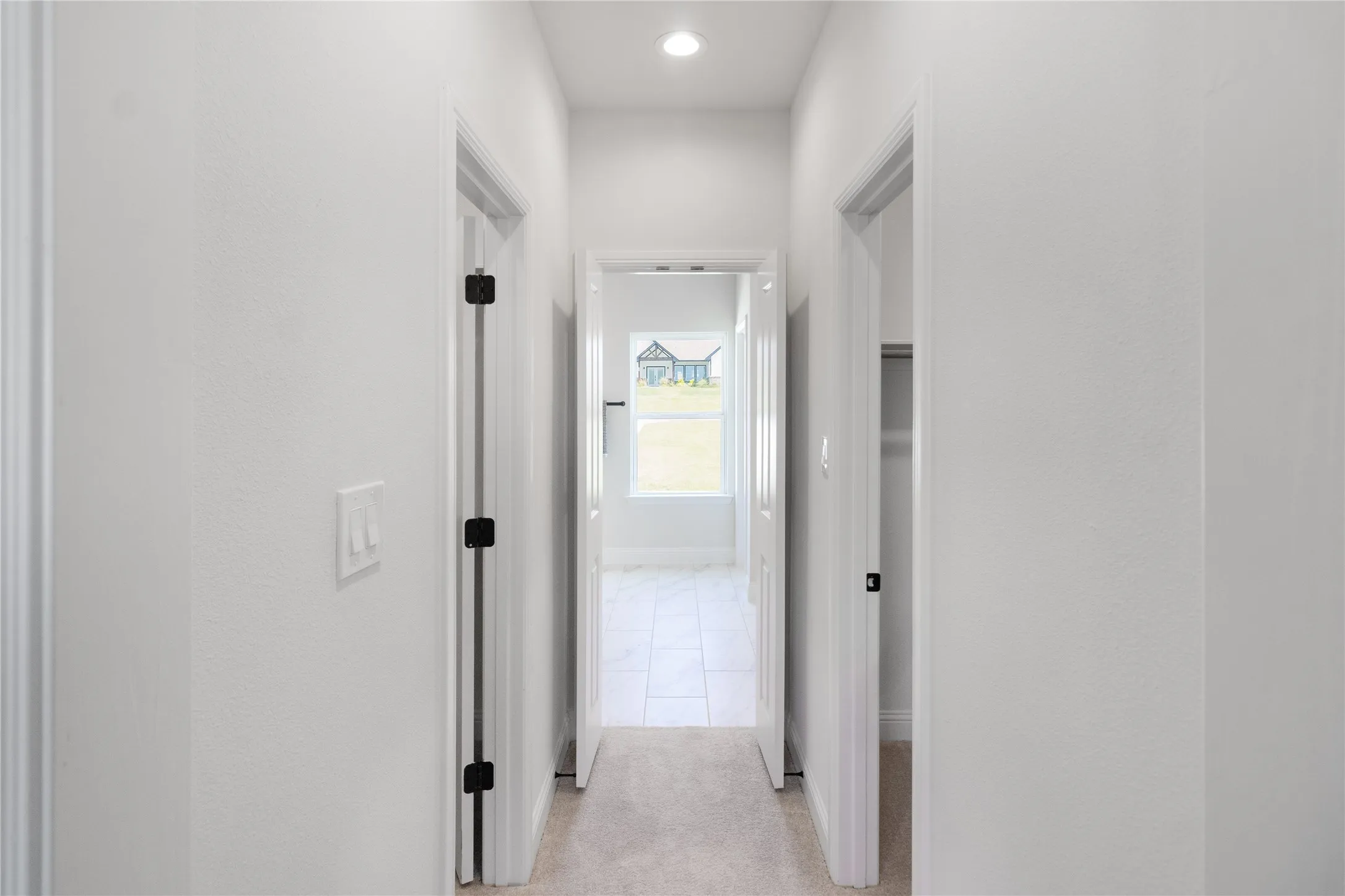 Hallway featuring light gray carpeting, white walls, recessed ceiling lighting, and multiple white doors with black hardware