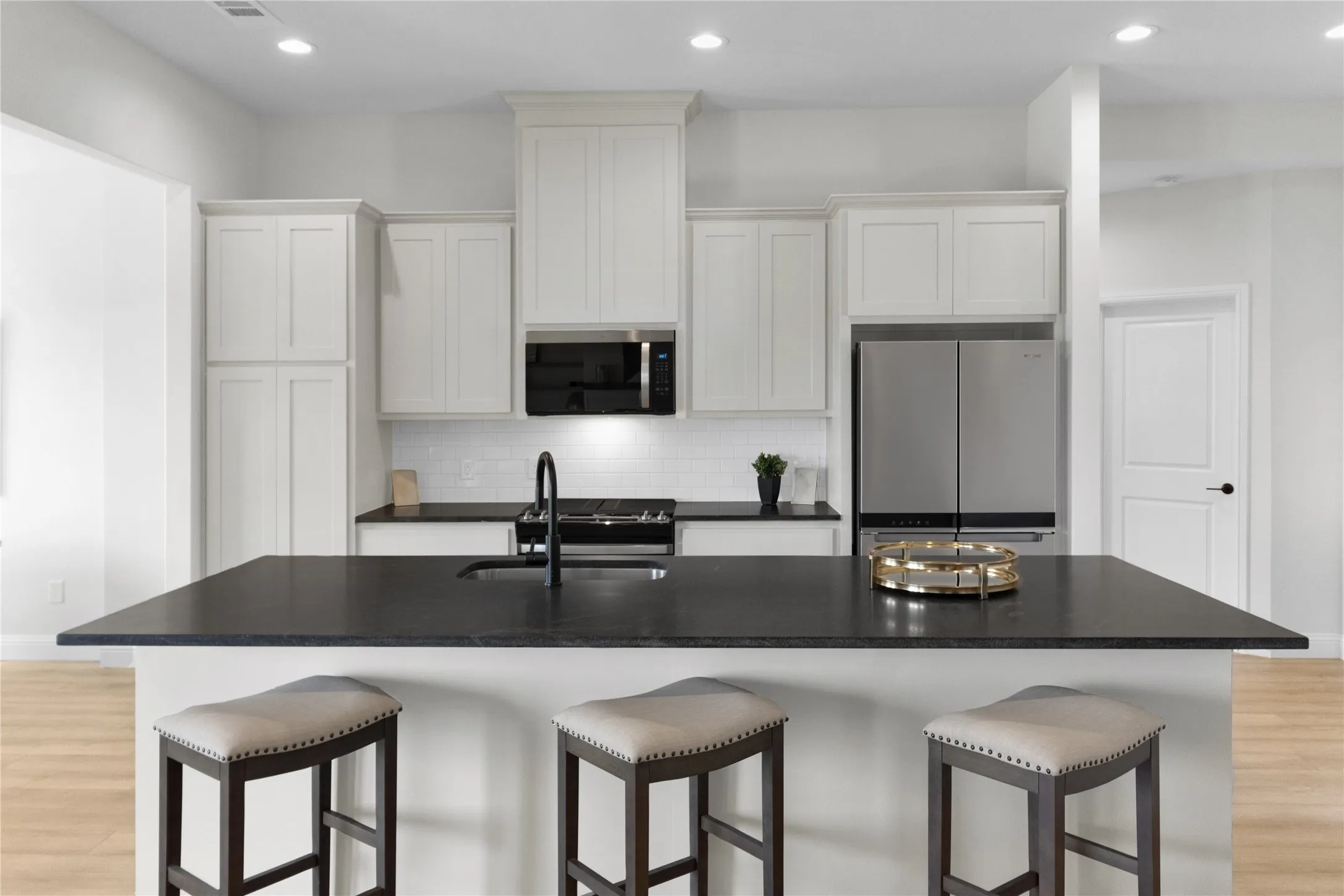 Kitchen island with dark countertop, integrated sink, and black faucet