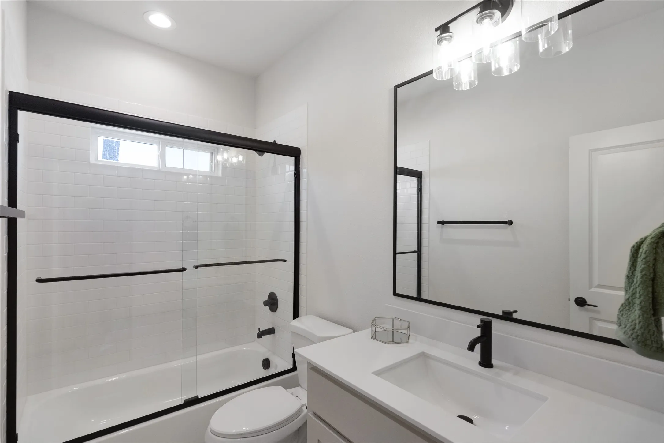Bathroom featuring a tub/shower combination with sliding glass doors, white subway tile surround, and an upper transom window