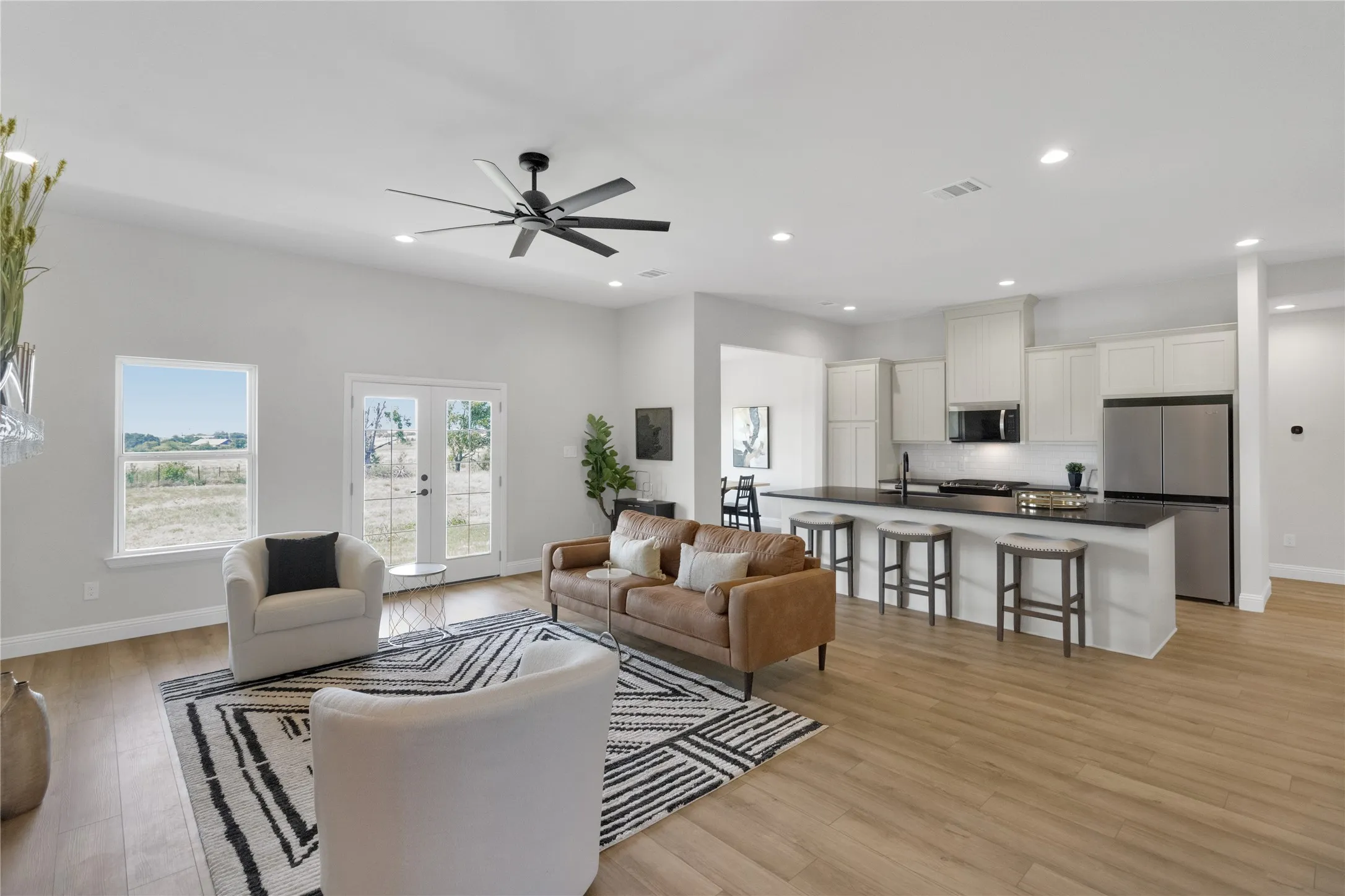 Expansive open-concept living area featuring wood-finish flooring, recessed lighting, and a modern ceiling fan