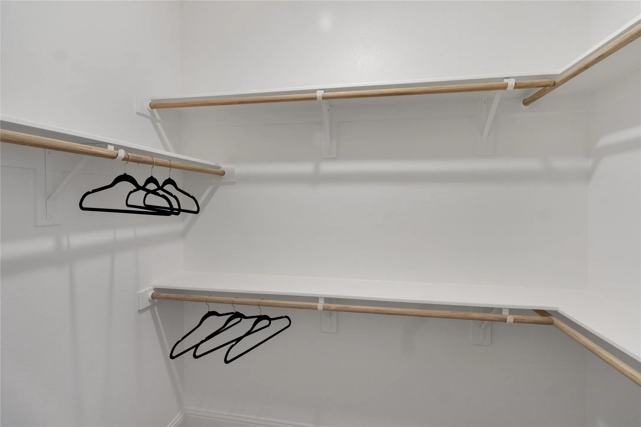 Built-in closet system featuring white shelving and wooden hanging rods