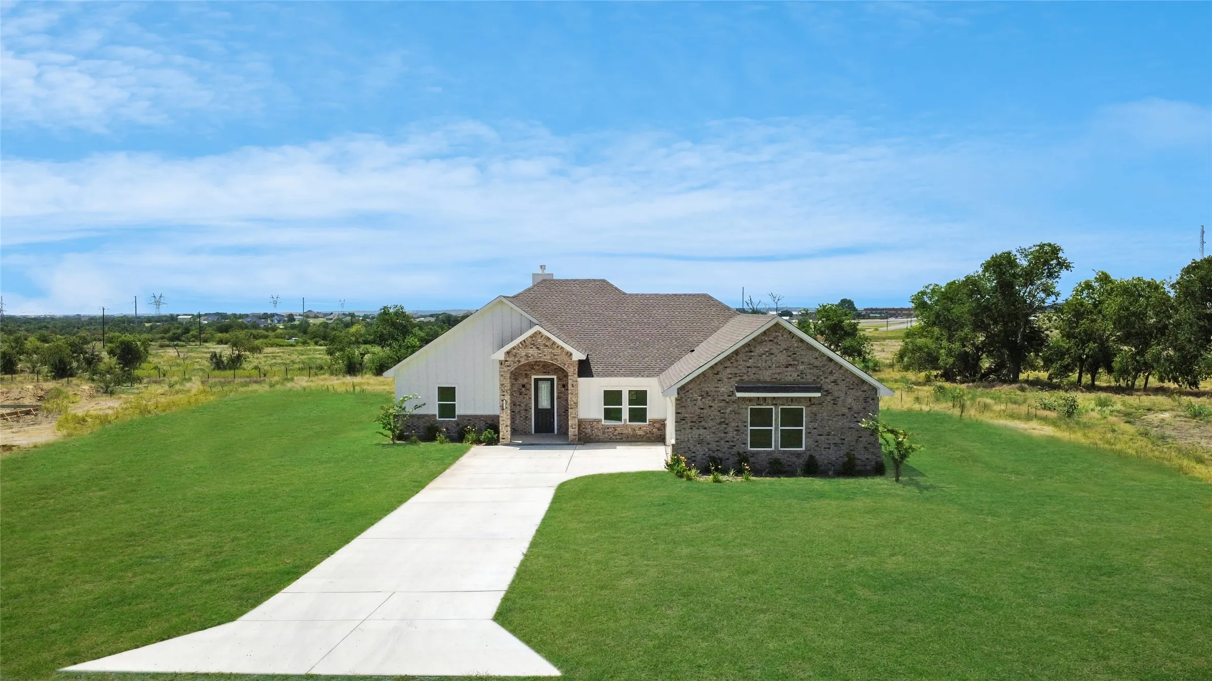 Single-story residence featuring a combination of brick and vertical panel siding, a dark shingle roof, and a prominent front entry with a dark door
