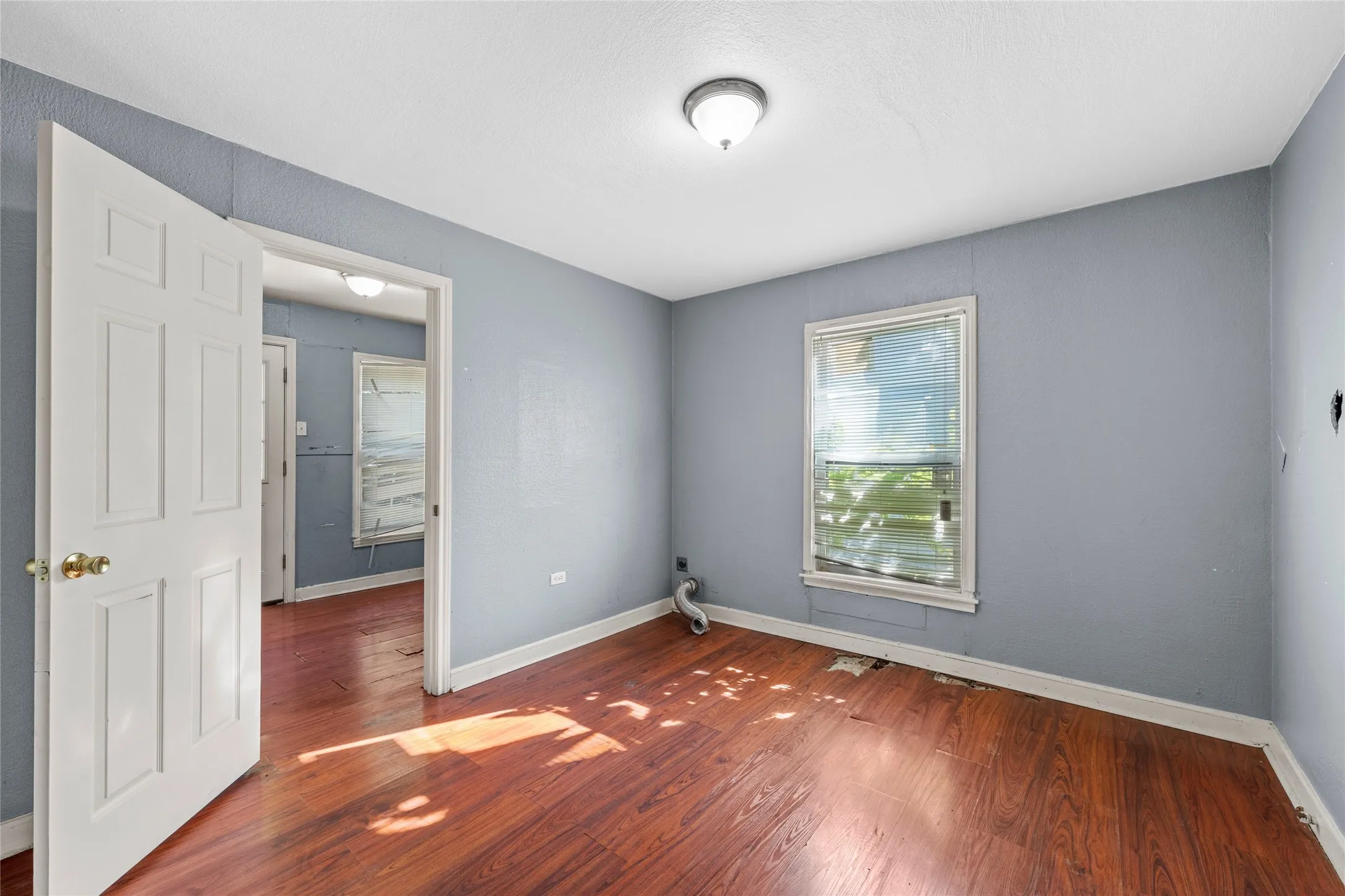 Interior space with wood-finish flooring, light blue wall paint, and white trim molding