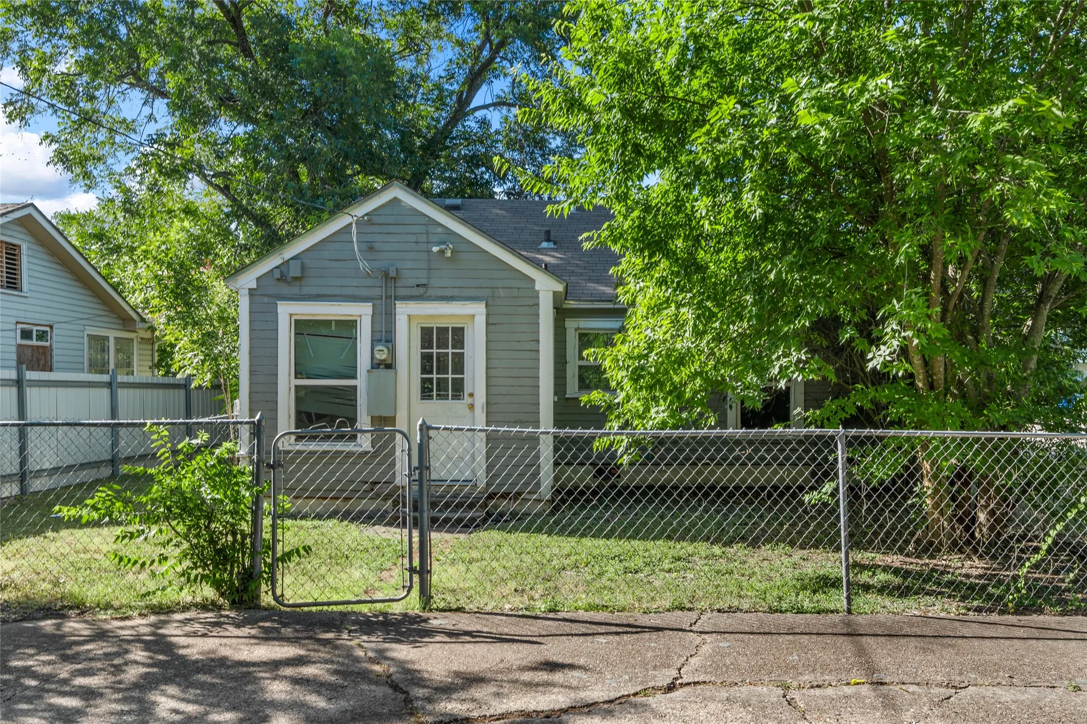 Exterior featuring horizontal siding, a fenced yard, mature trees, and a gabled roofline