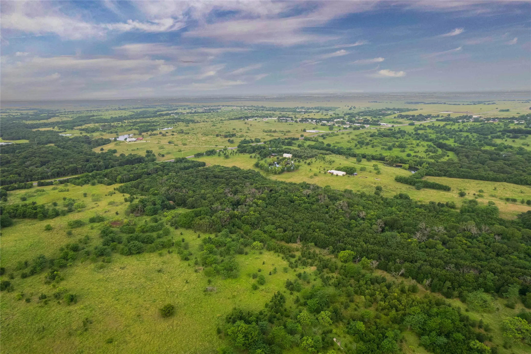 Expansive rural landscape featuring extensive green acreage and mature tree coverage