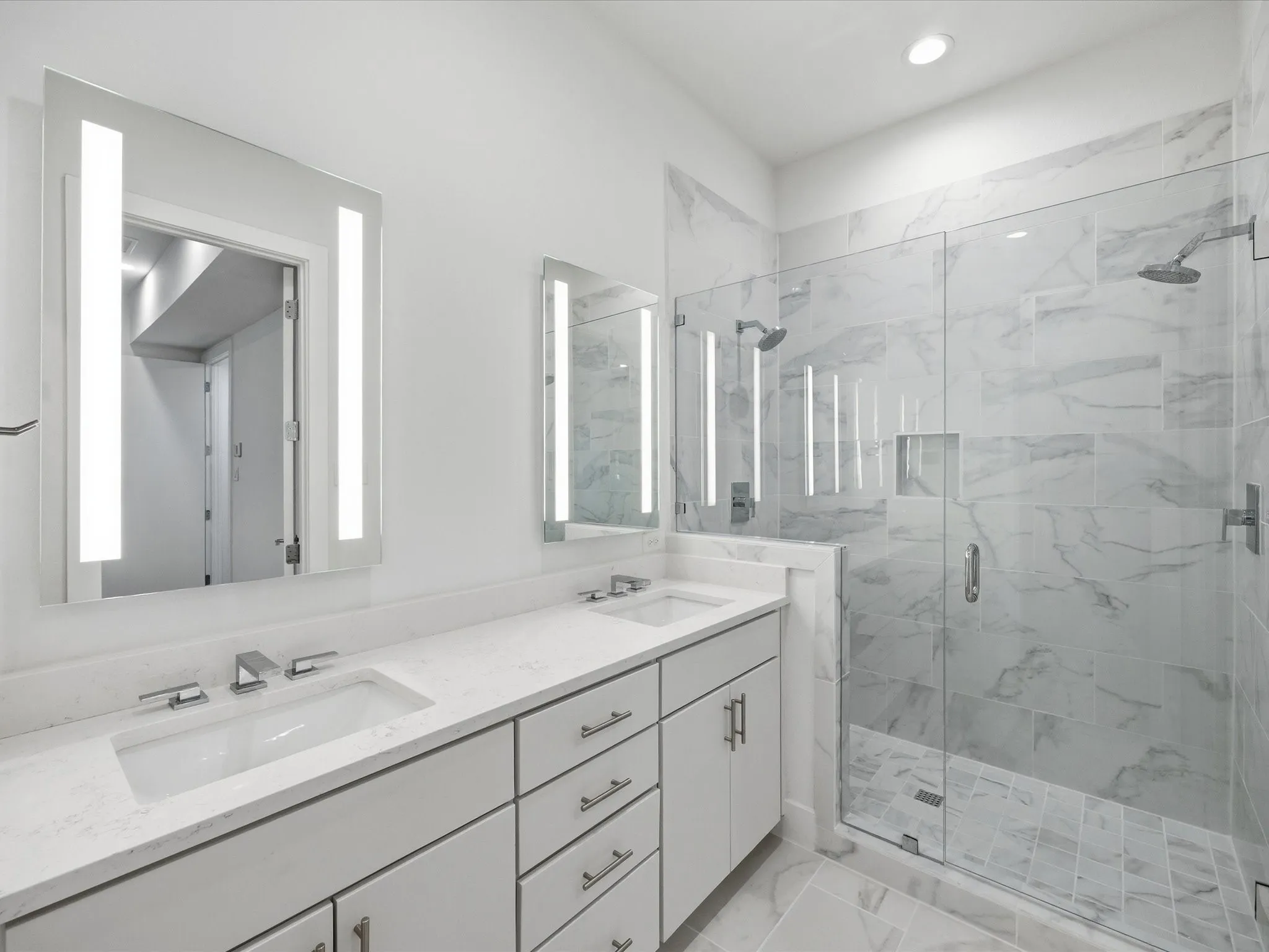 Bathroom featuring double vanity, a marble finish shower, and recessed lighting