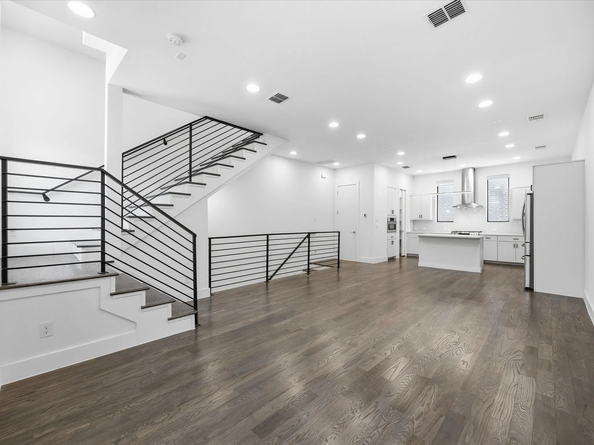 Unfurnished living room featuring dark wood-style flooring and recessed lighting
