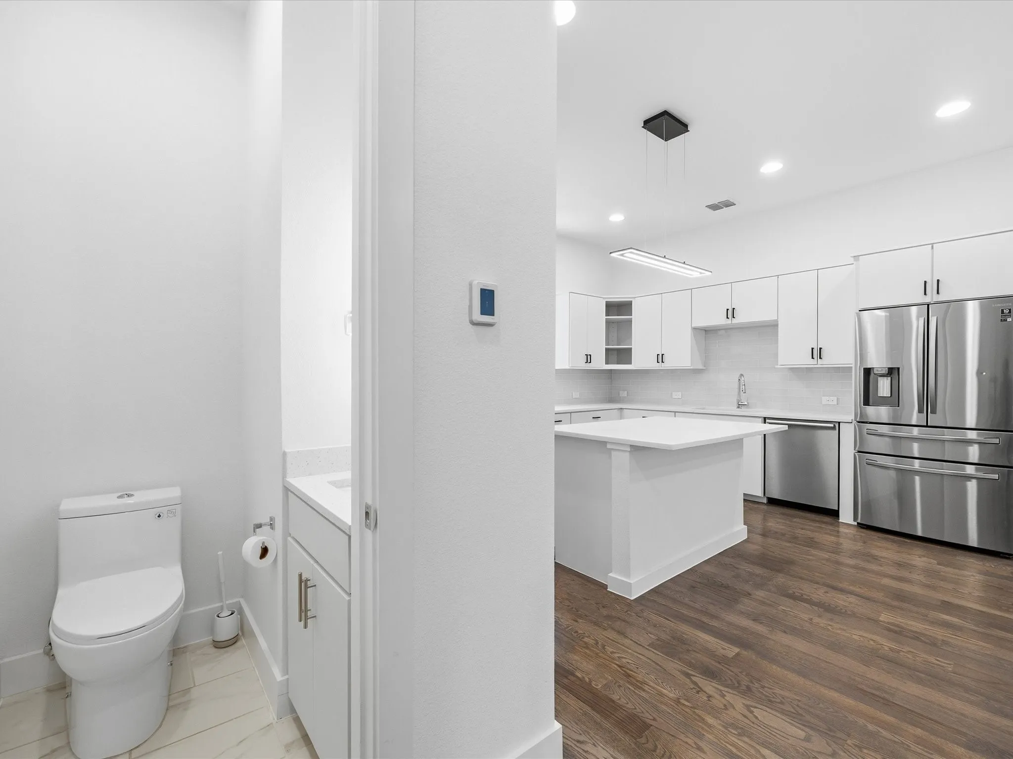 Kitchen with white cabinets, stainless steel appliances, glass insert cabinets, hanging light fixtures, and tasteful backsplash