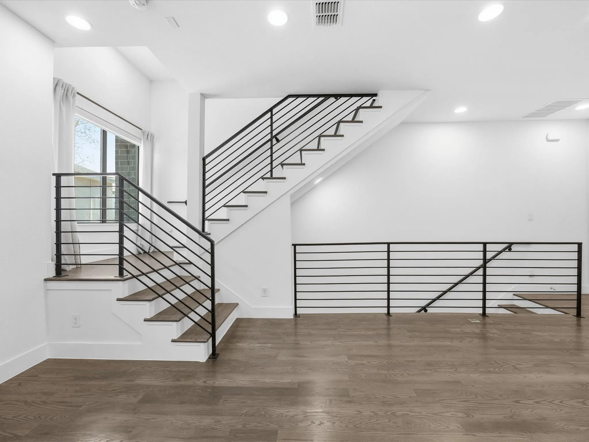 Stairway with wood finished floors and recessed lighting