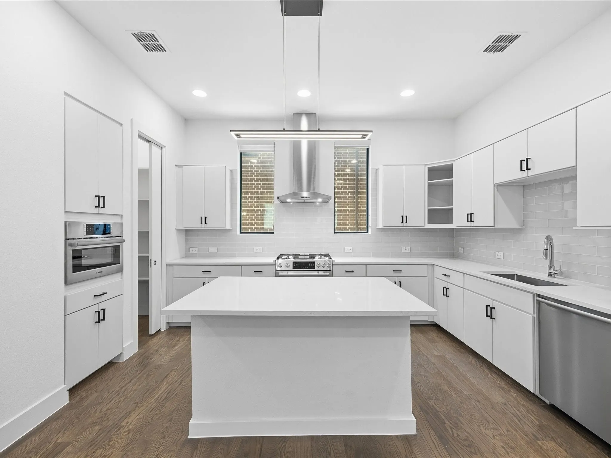 Kitchen with stainless steel appliances, white cabinets, dark wood-style floors, and a center island