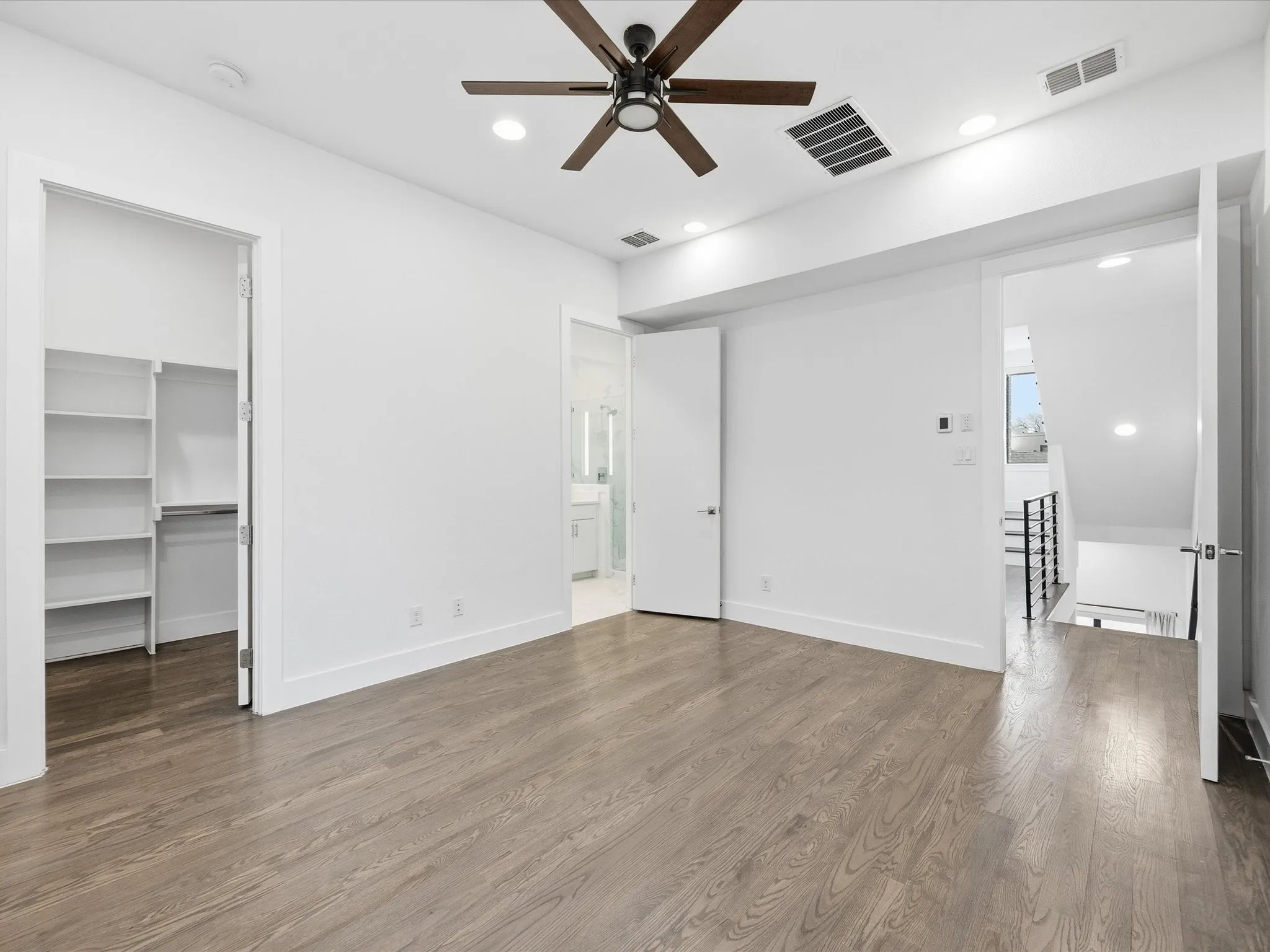 Unfurnished bedroom featuring a walk in closet, wood finished floors, recessed lighting, and a ceiling fan