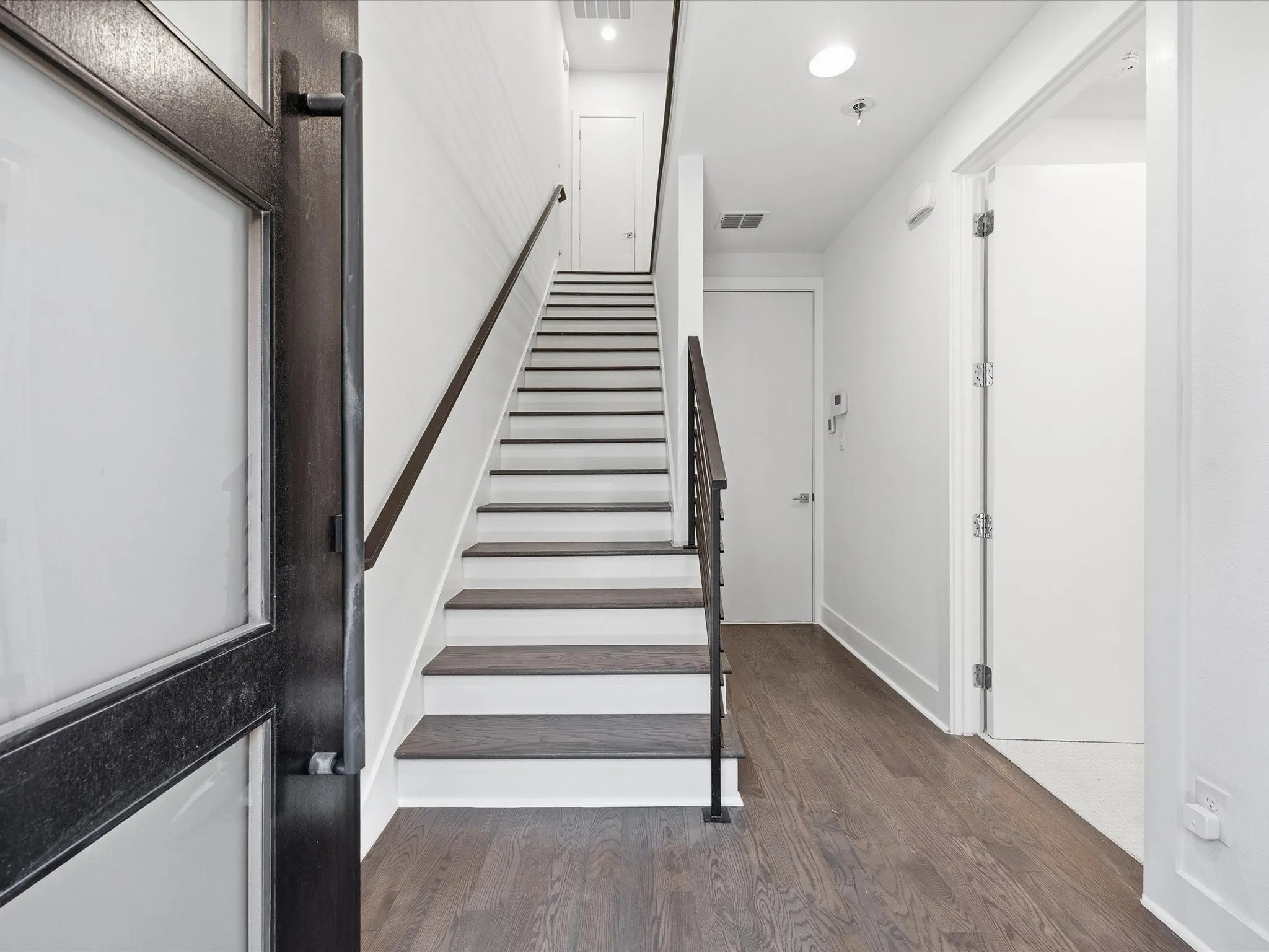 Stairway featuring wood finished floors and recessed lighting