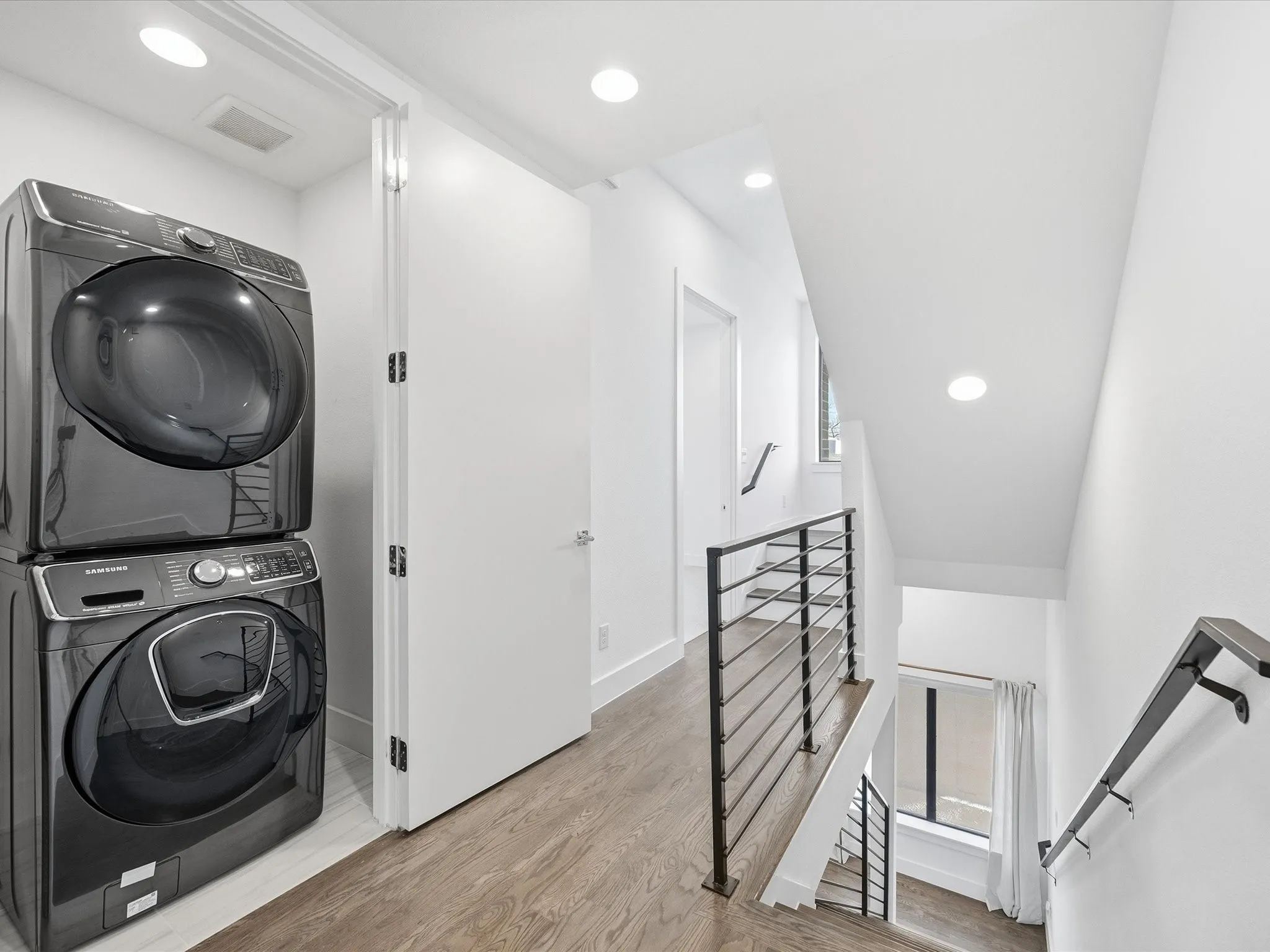 Laundry area featuring stacked washer / dryer, light wood finished floors, and recessed lighting