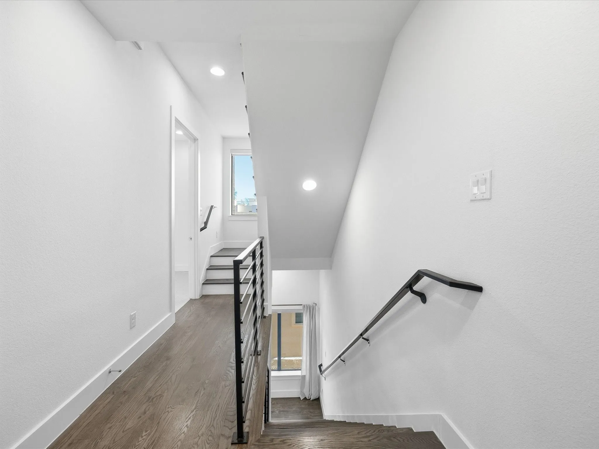 Stairway with wood finished floors and recessed lighting