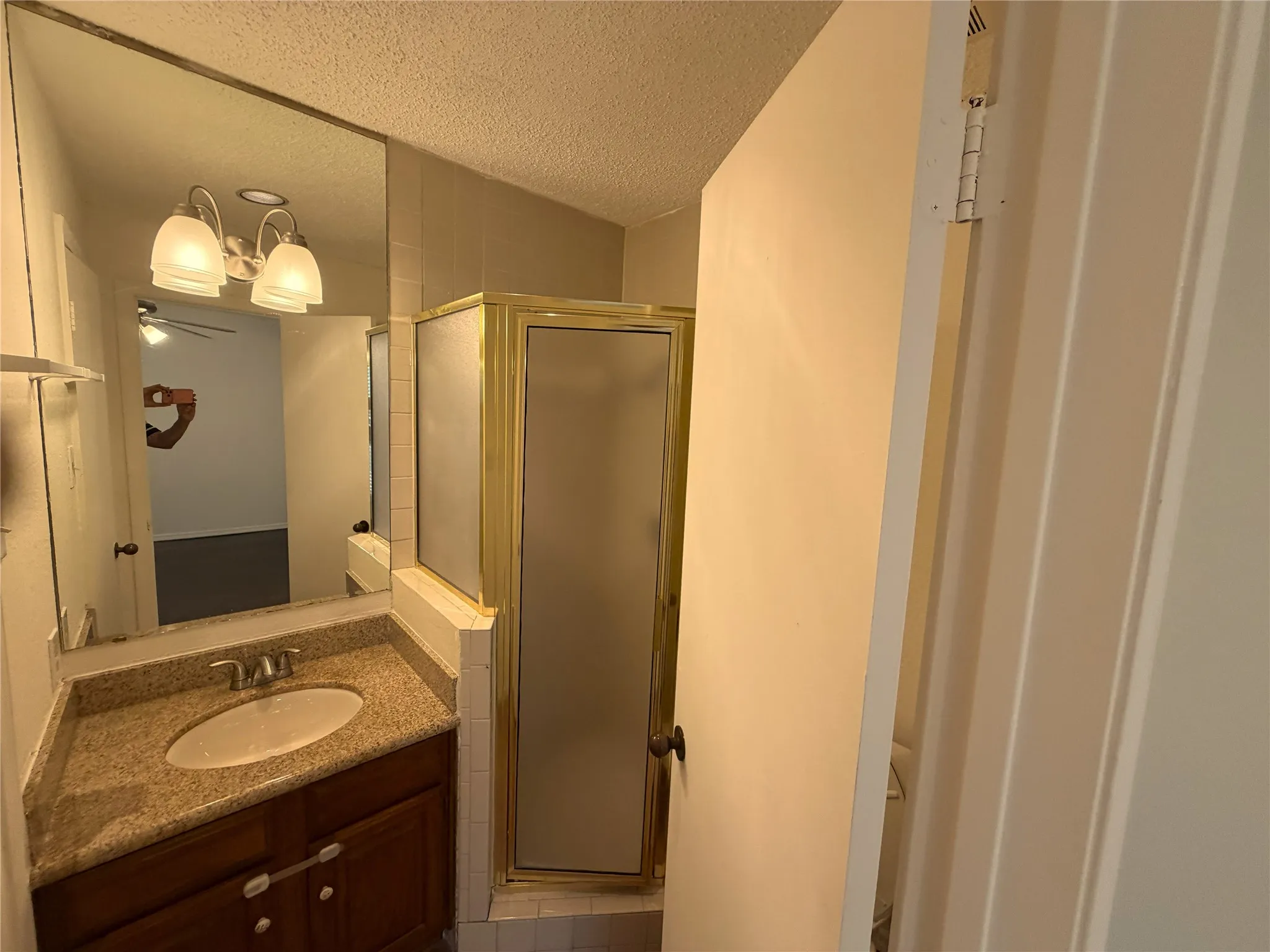 Bathroom featuring a vanity with a light-toned stone-finish countertop, an oval undermount sink, and a dark wood-finish cabinet