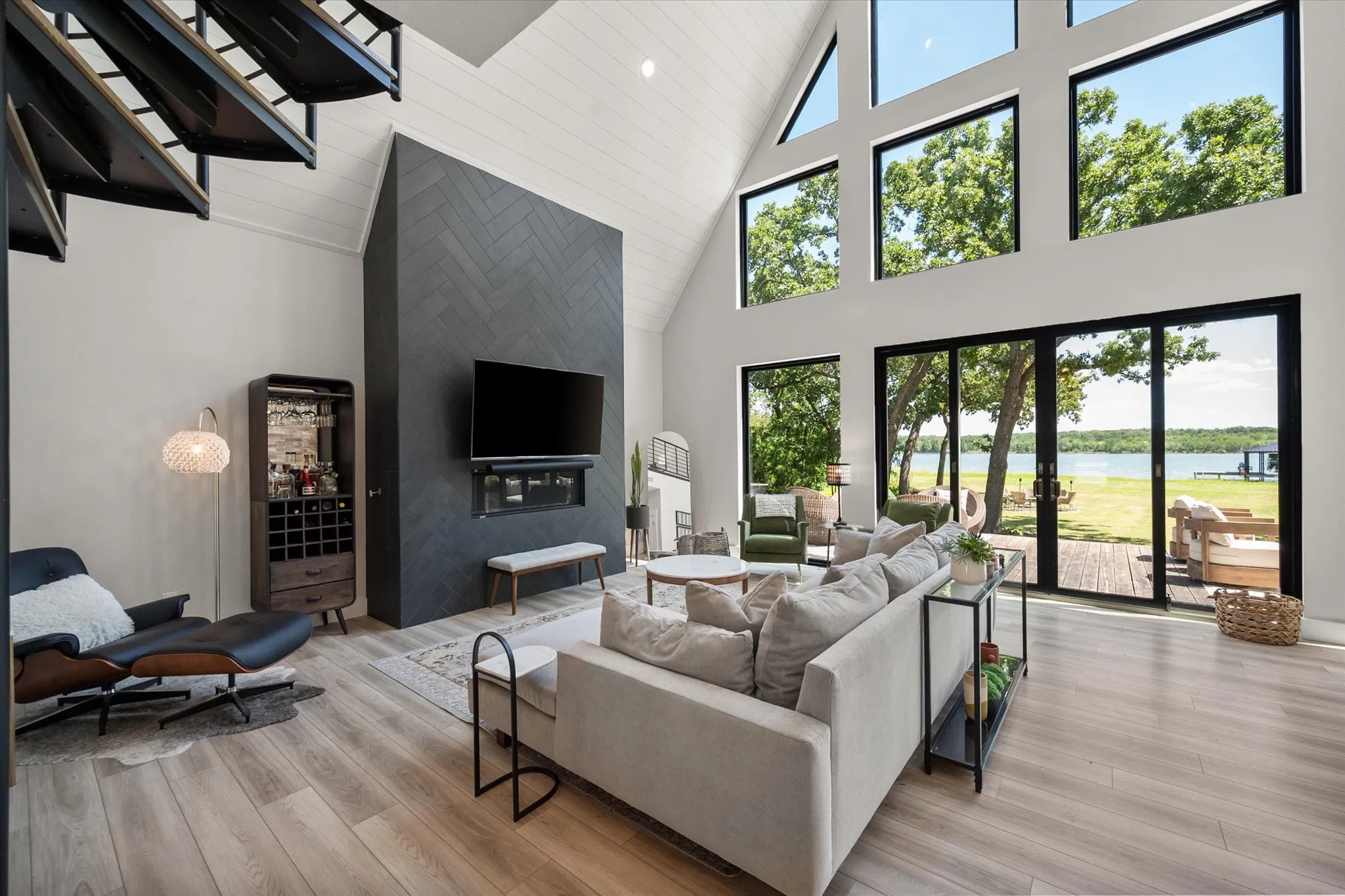 Contemporary living room features soaring ceilings, luxury vinyl plank flooring, and waterfront views.
