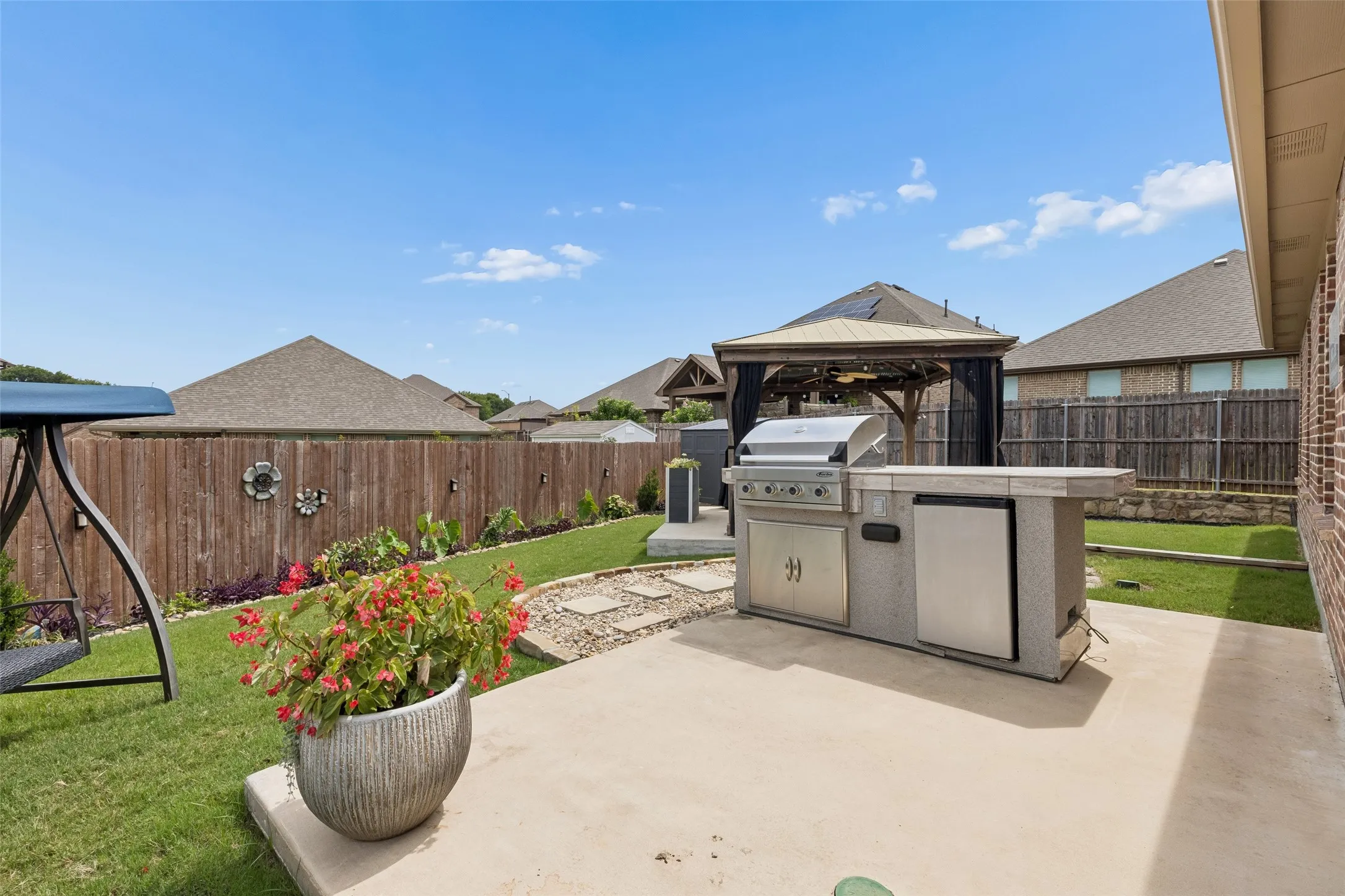 Outdoor cooking station with a refrigerator and grill.