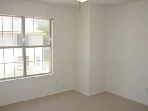 Bright interior room featuring a large window with grid panes, textured wall finish, and a ceiling-mounted light fixture
