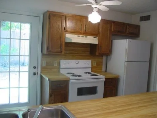 Kitchen featuring wood-finish countertops and backsplash, wood cabinetry, and a white electric range with matching overhead hood