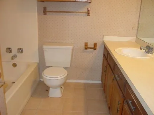 Bathroom featuring a single vanity with wood-finish cabinetry, a white drop-in sink, and a light-toned countertop