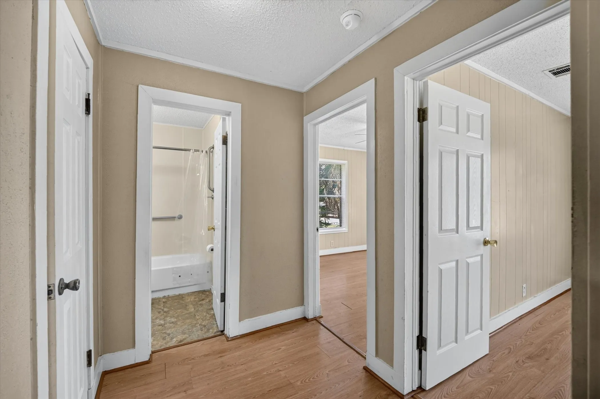 Hallway featuring wood-finish flooring, neutral wall paint, and white trim