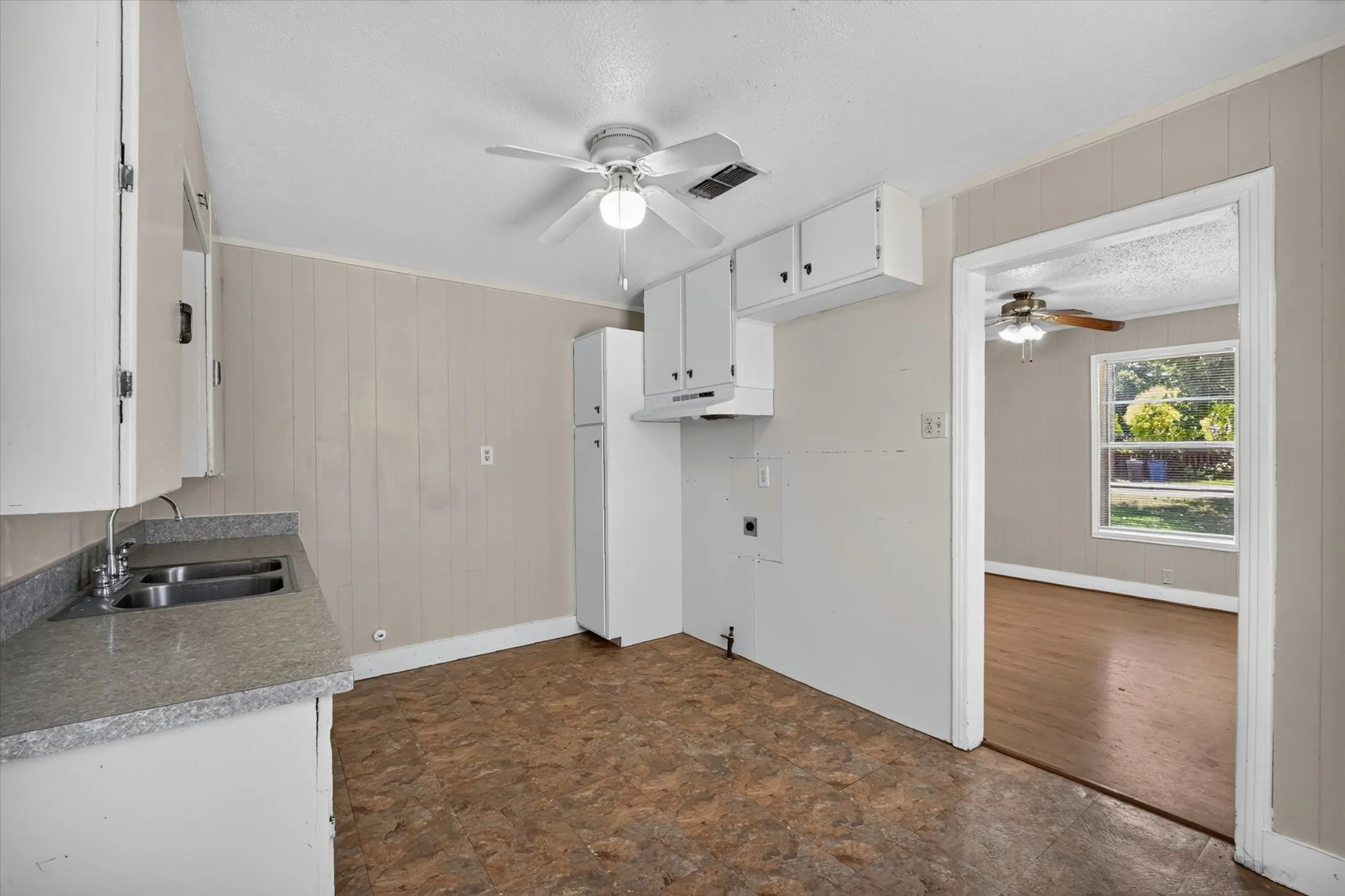 Kitchen featuring white cabinetry, a double basin stainless steel sink, and gray speckled countertops