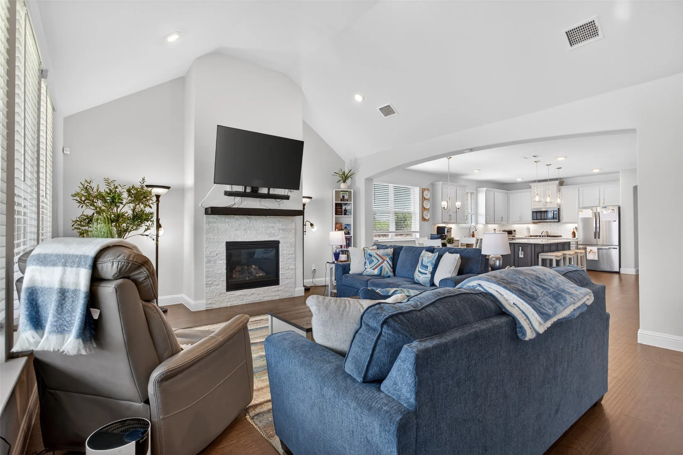 Spacious living area featuring a vaulted ceiling, recessed lighting, and wood-finish flooring