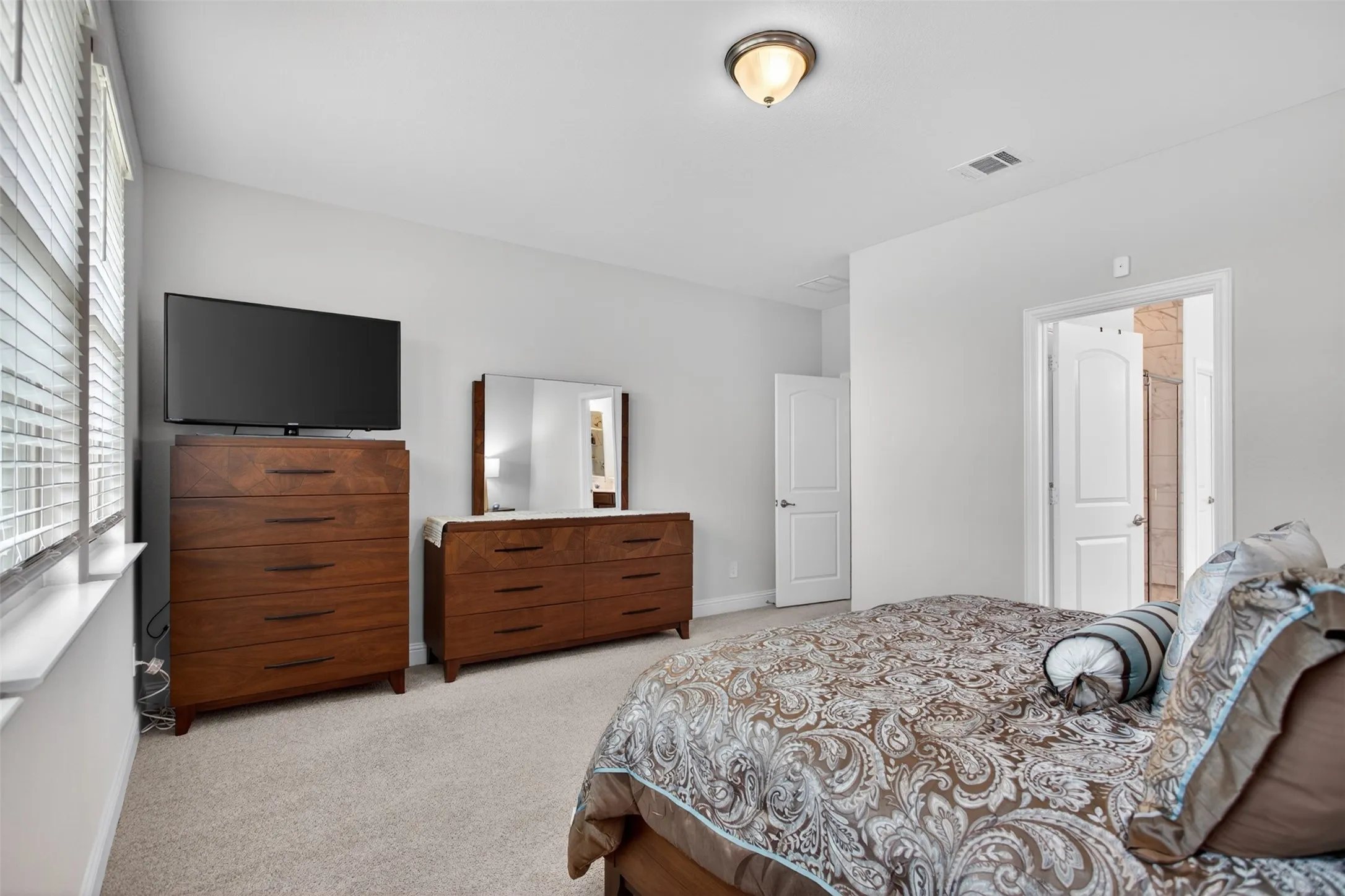Carpeted bedroom featuring neutral wall tones, a ceiling-mounted light fixture, and an arched interior doorway