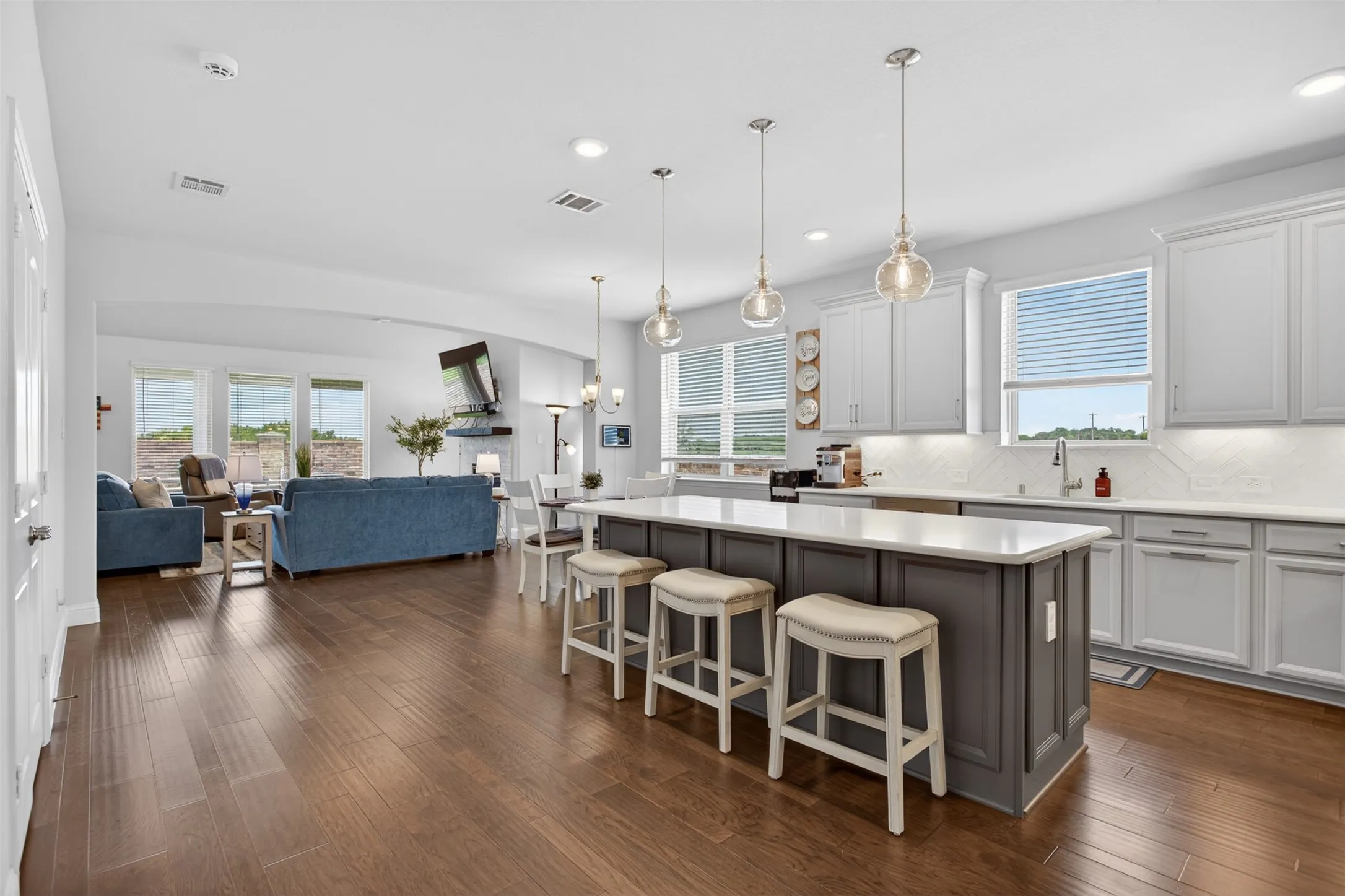 Spacious kitchen featuring a large island with seating, white shaker-style cabinetry, light countertops, and a white subway tile backsplash